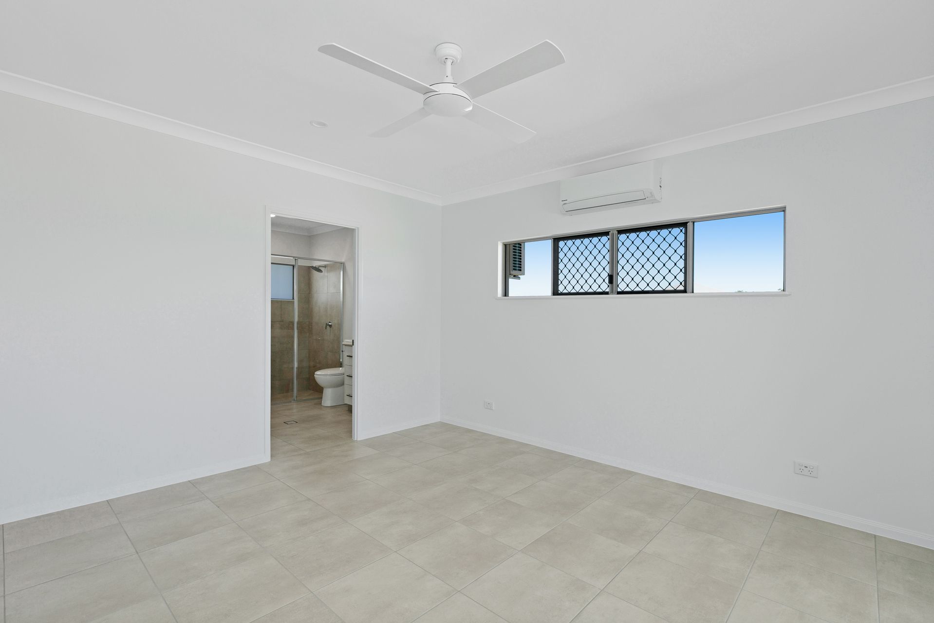 A Spacious, Empty Room With White Walls, Light-colored Tiled Flooring — Ashlee Jones Homes in Gordonvale, QLD
