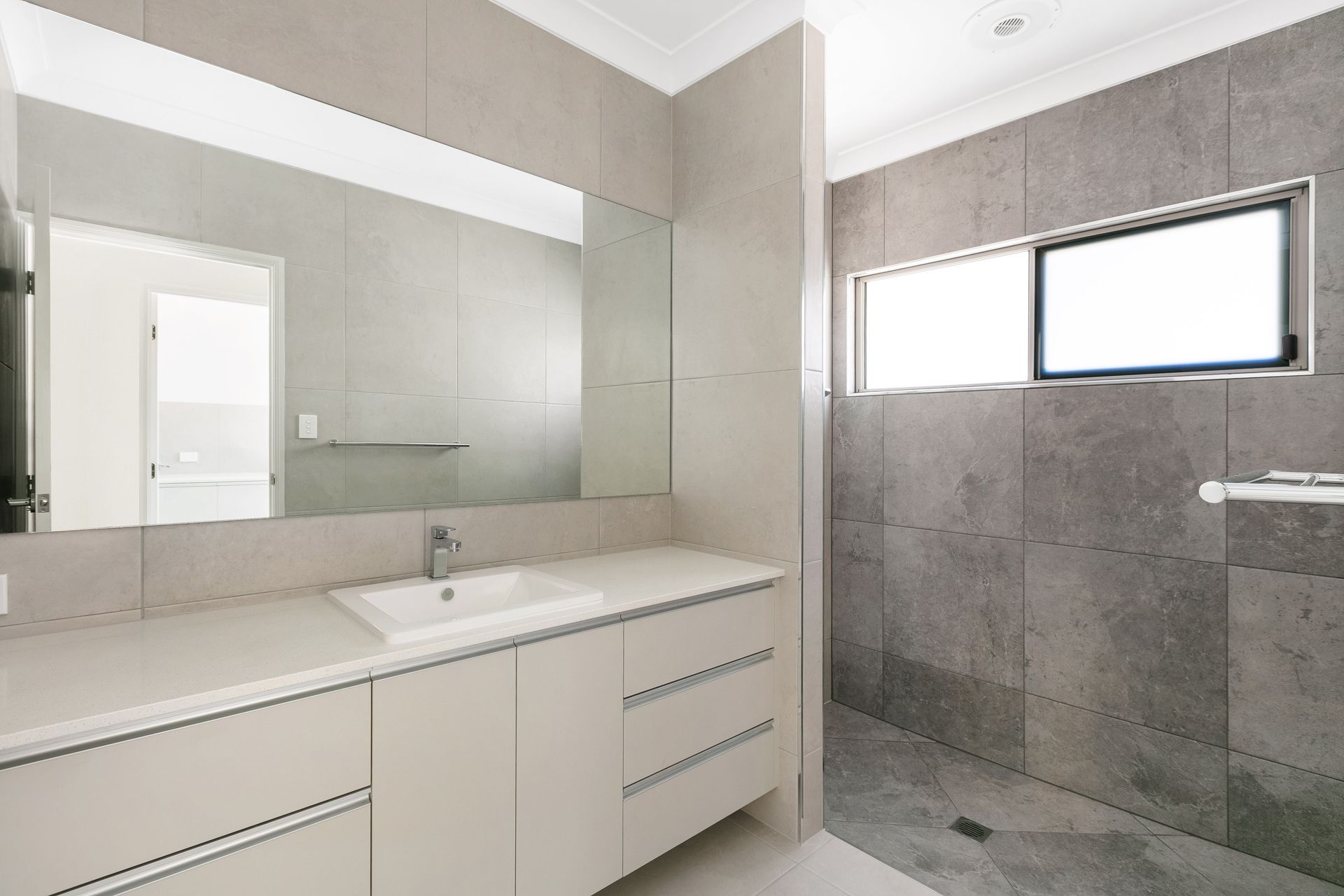 A Modern Bathroom Featuring a Light Gray Vanity With a Sink — Ashlee Jones Homes in Gordonvale, QLD
