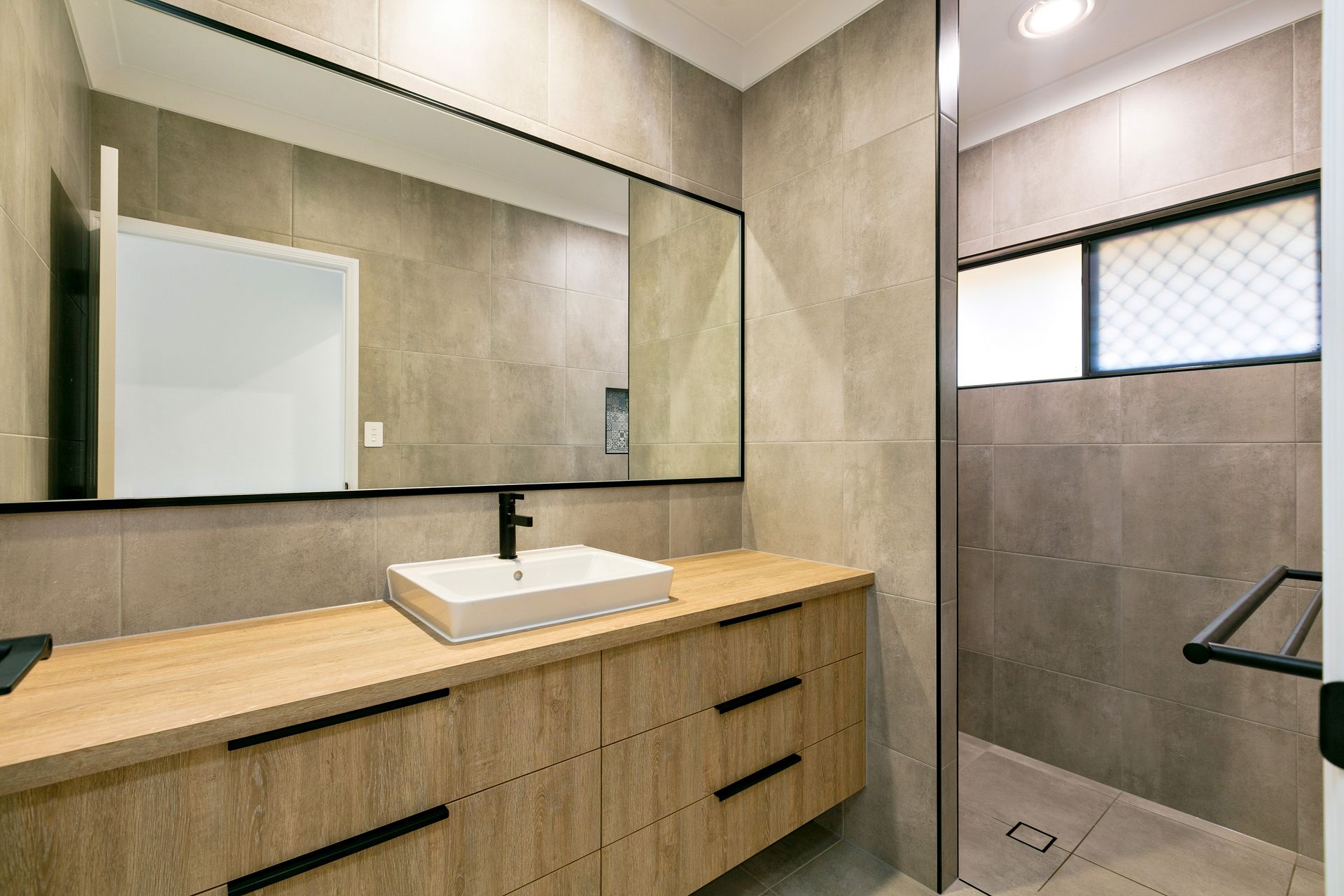 A Modern Bathroom Vanity With a Wood-grain Cabinet — Ashlee Jones Homes in Gordonvale, QLD