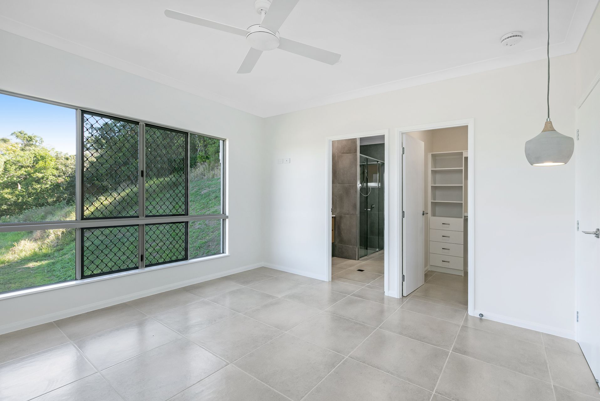 A Bright, Empty Bedroom With Tiled Floors — Ashlee Jones Homes in Gordonvale, QLD