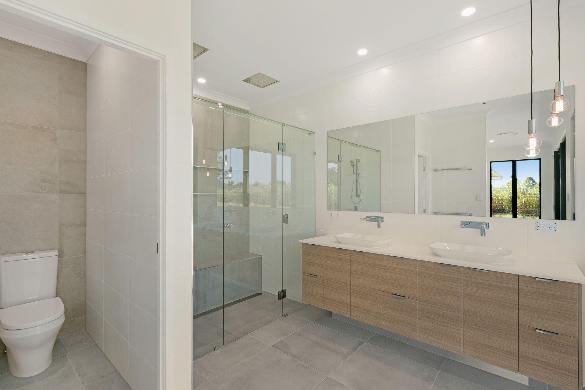 Modern Bathroom With a Light Wood Double Vanity, Large Mirror — Ashlee Jones Homes in Gordonvale, QLD