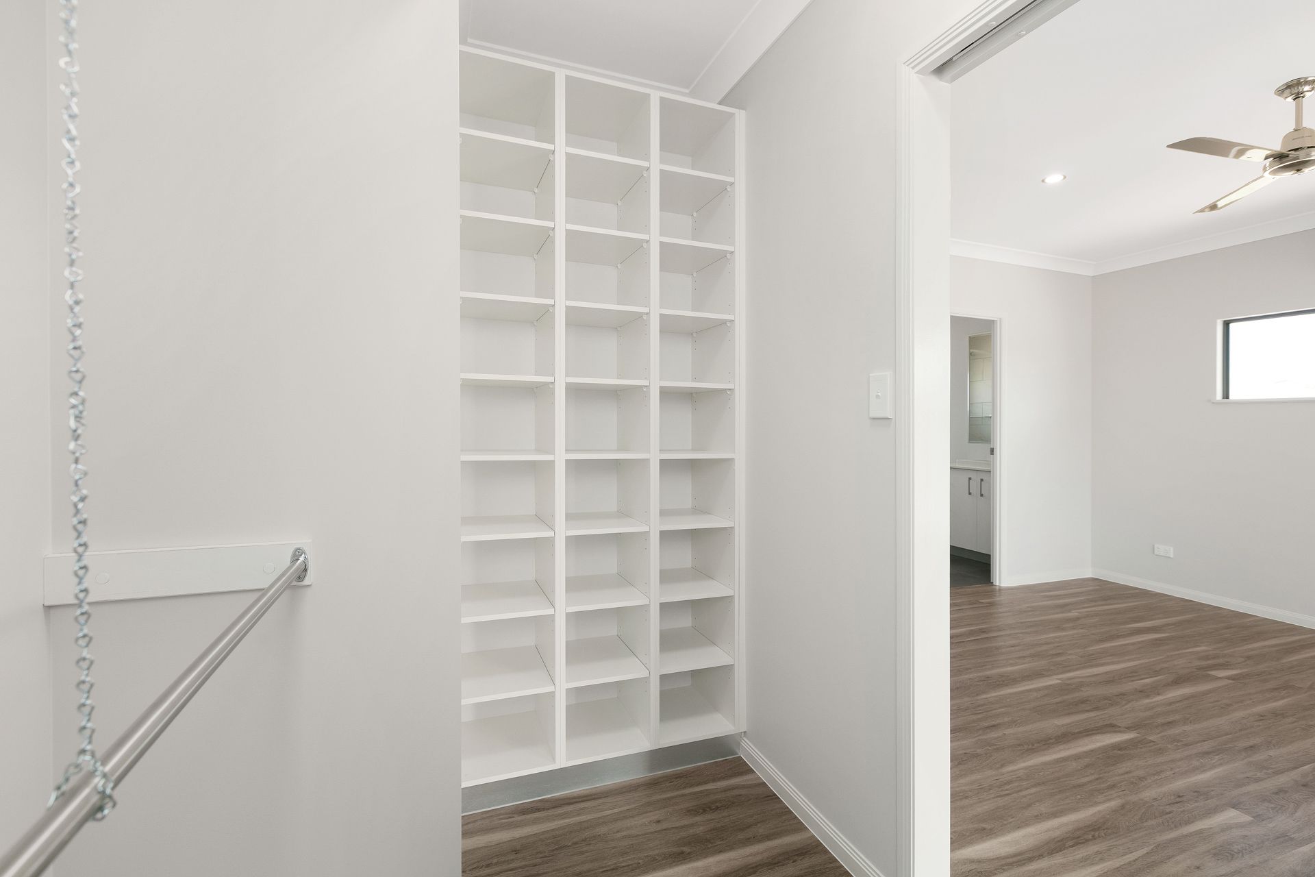 A Walk-in Closet Featuring Floor-to-ceiling White Shelving and a Hanging Rod — Ashlee Jones Homes in Gordonvale, QLD