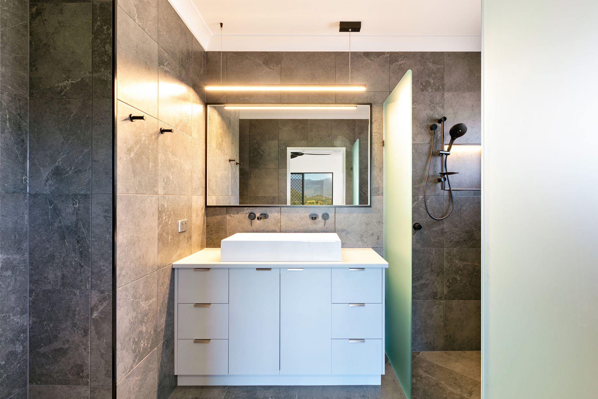 A Modern Bathroom With Grey Stone Walls — Ashlee Jones Homes in Gordonvale, QLD
