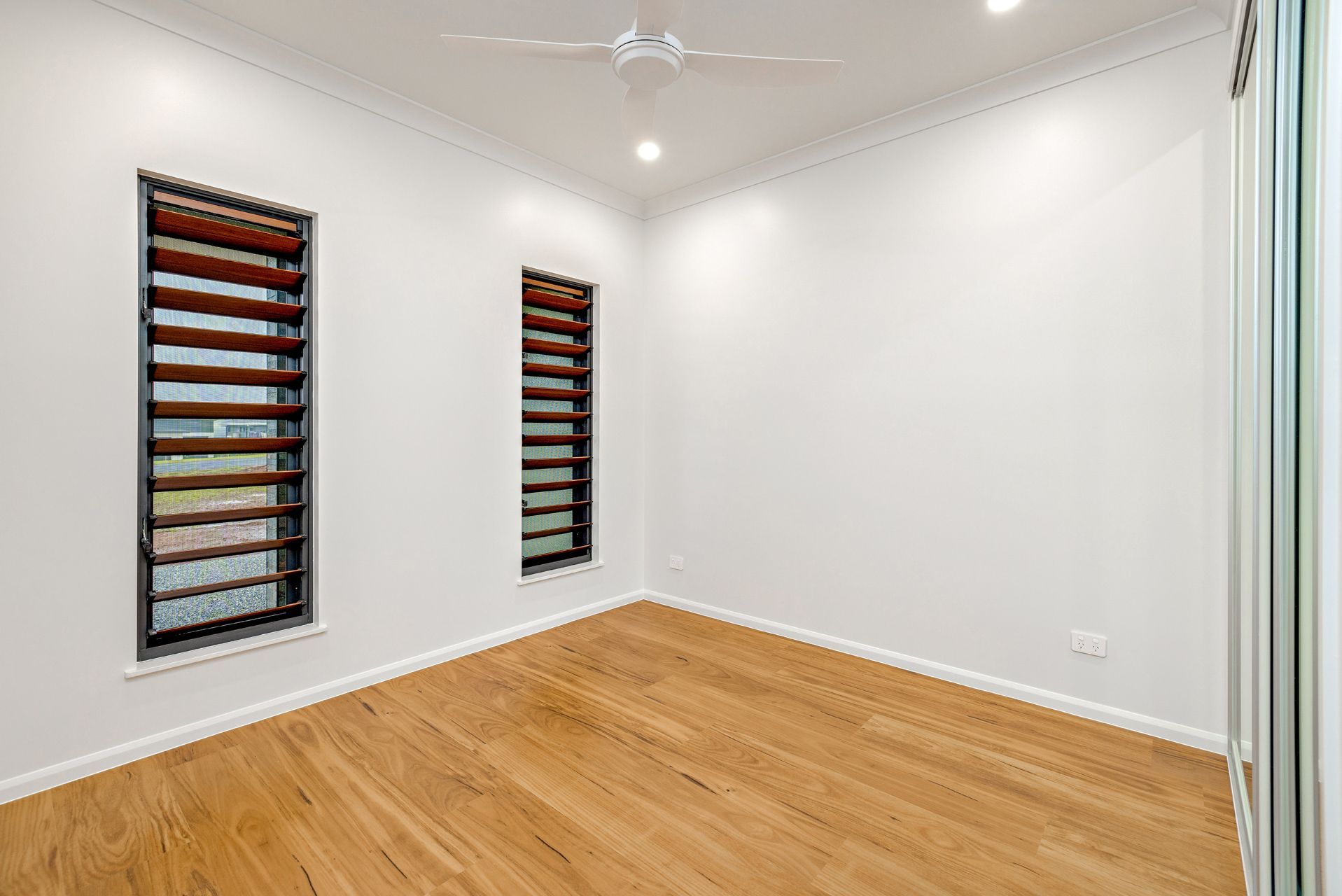 An Empty Room With White Walls, Light-toned Wood Flooring — Ashlee Jones Homes in Gordonvale, QLD