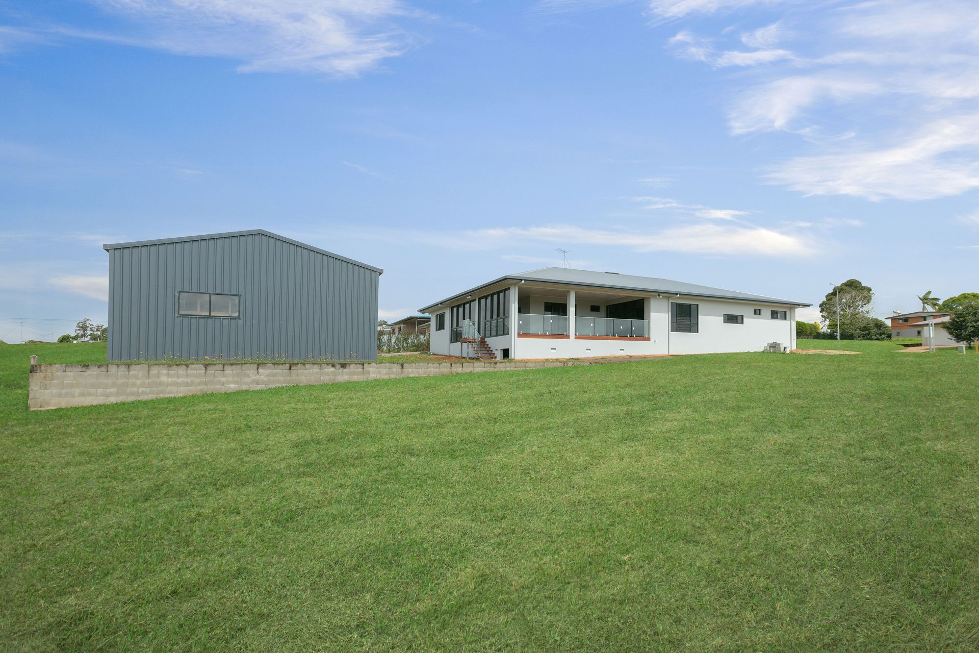 A White House With a Porch and a Detached Gray Metal Shed — Ashlee Jones Homes in Gordonvale, QLD