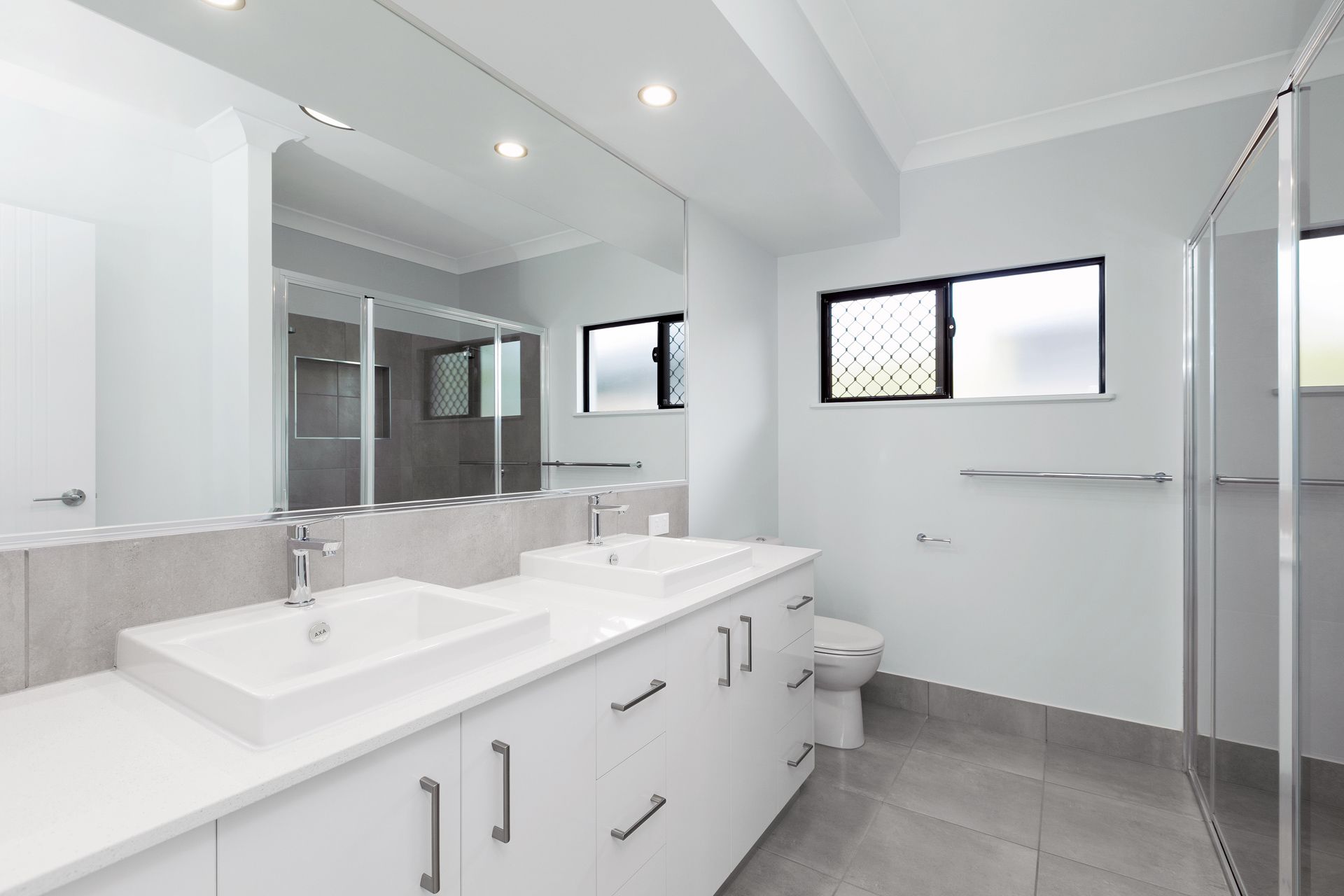 A Modern Bathroom Featuring a White Dual-sink Vanity — Ashlee Jones Homes in Gordonvale, QLD
