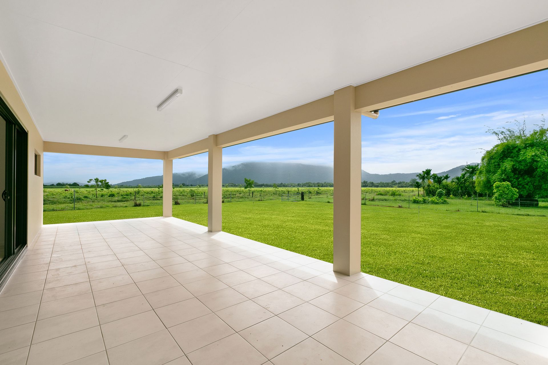 A Tiled Patio Under a Covered Roof Overlooks a Sprawling Green Lawn — Ashlee Jones Homes in Gordonvale, QLD