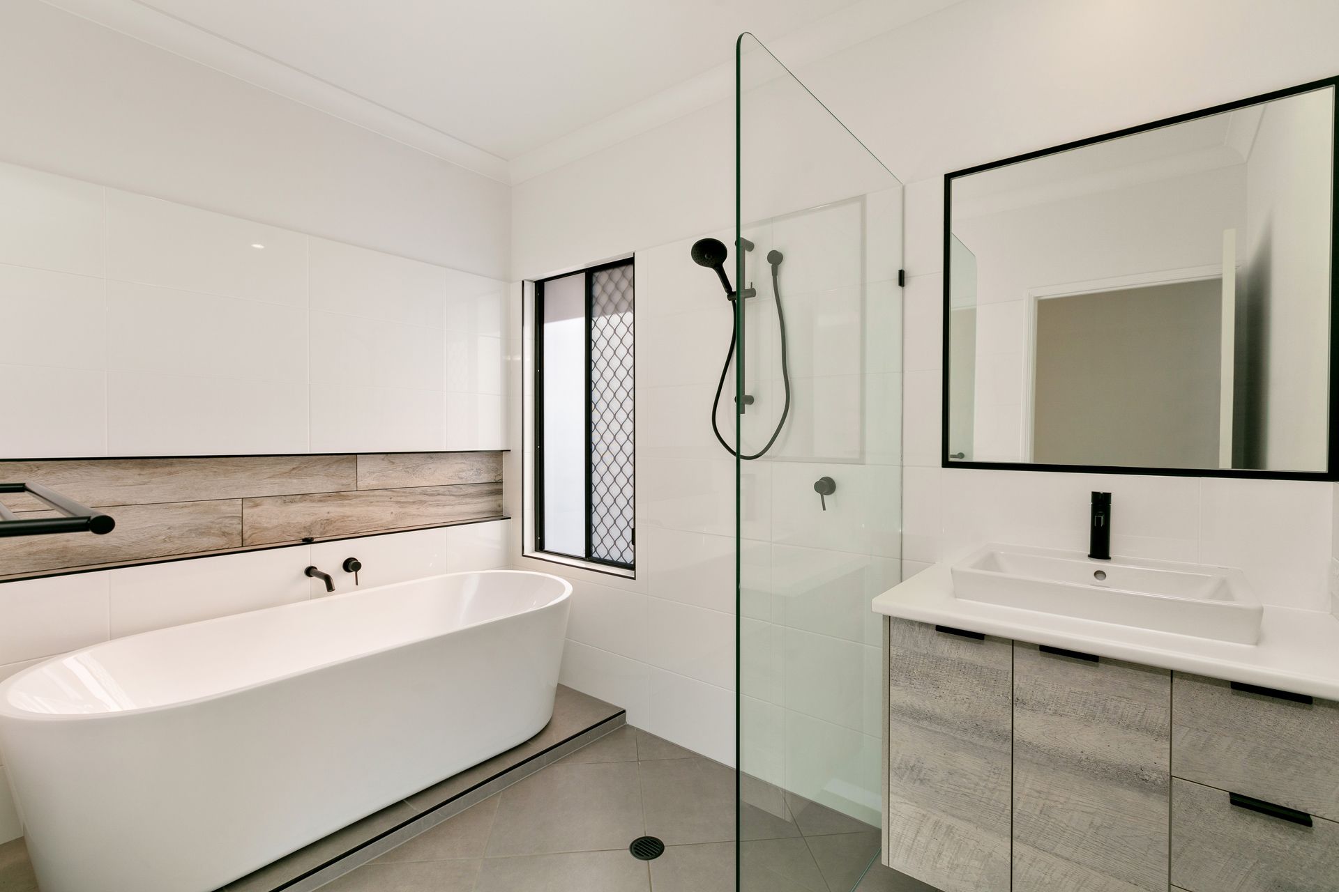 A Modern Bathroom Features a White Freestanding Bathtub — Ashlee Jones Homes in Gordonvale, QLD