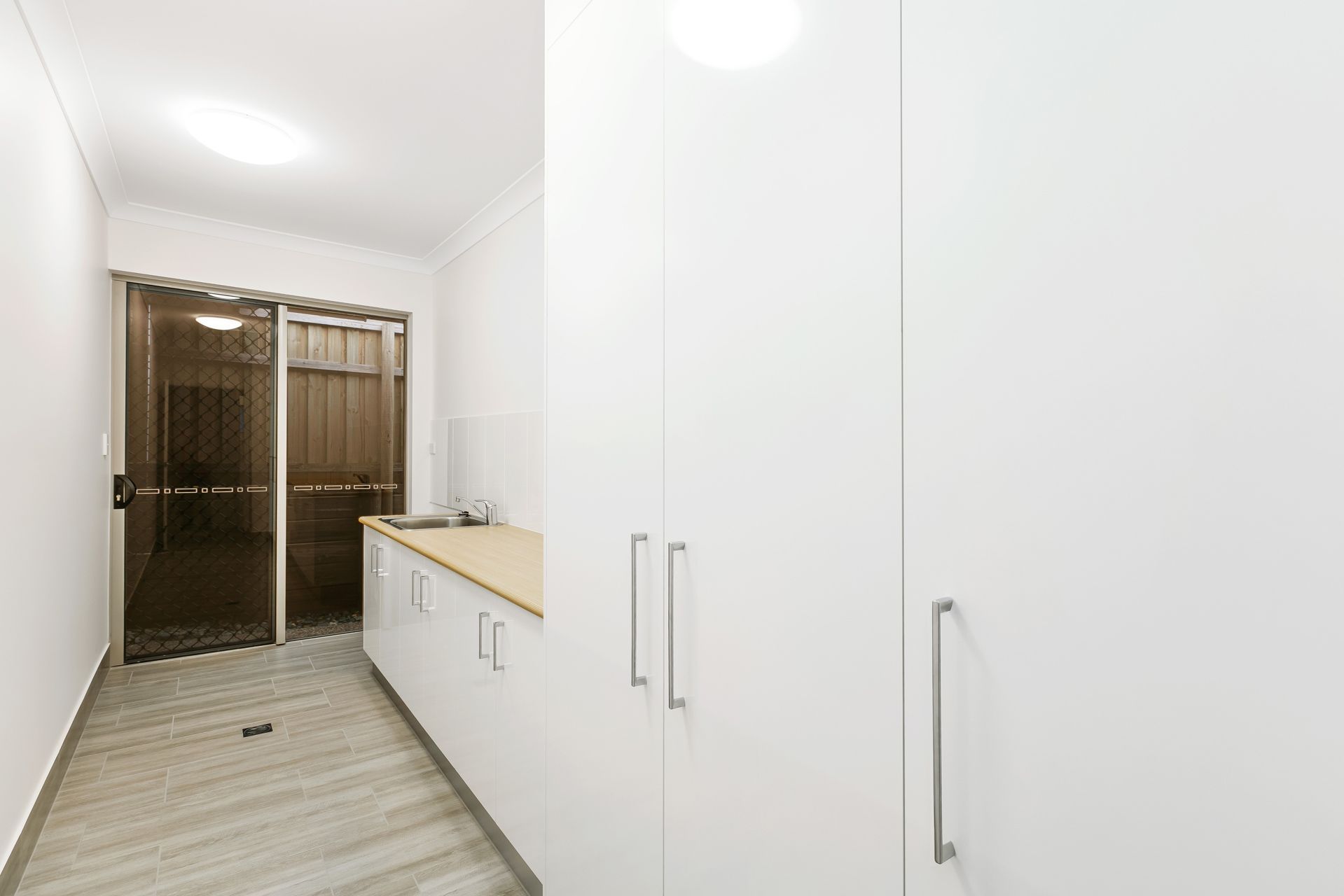 A Minimalist Hallway Featuring White Floor-to-ceiling Cabinets — Ashlee Jones Homes in Gordonvale, QLD