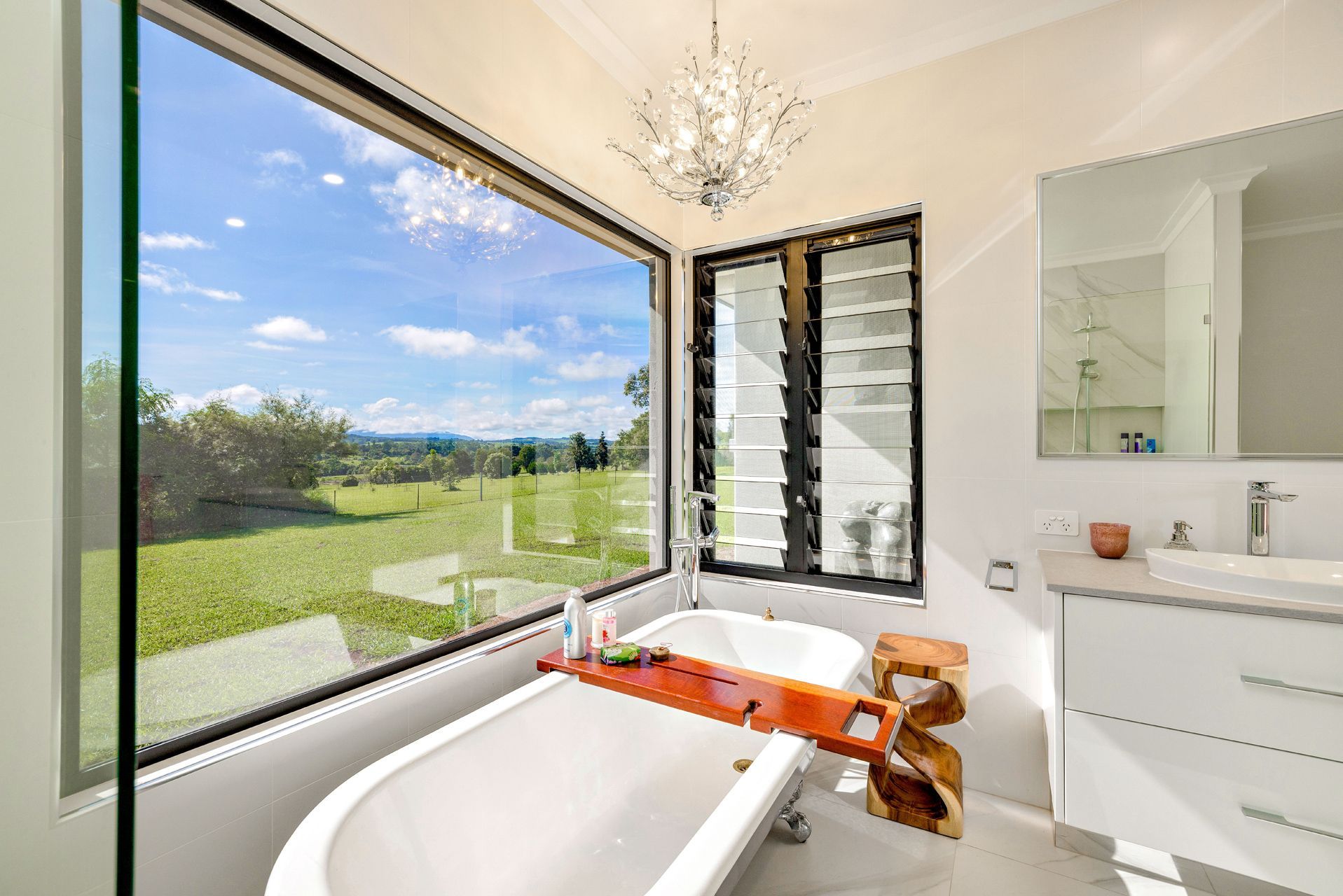 A Bright Bathroom With a White Soaking Tub by a Large Window — Ashlee Jones Homes in Gordonvale, QLD