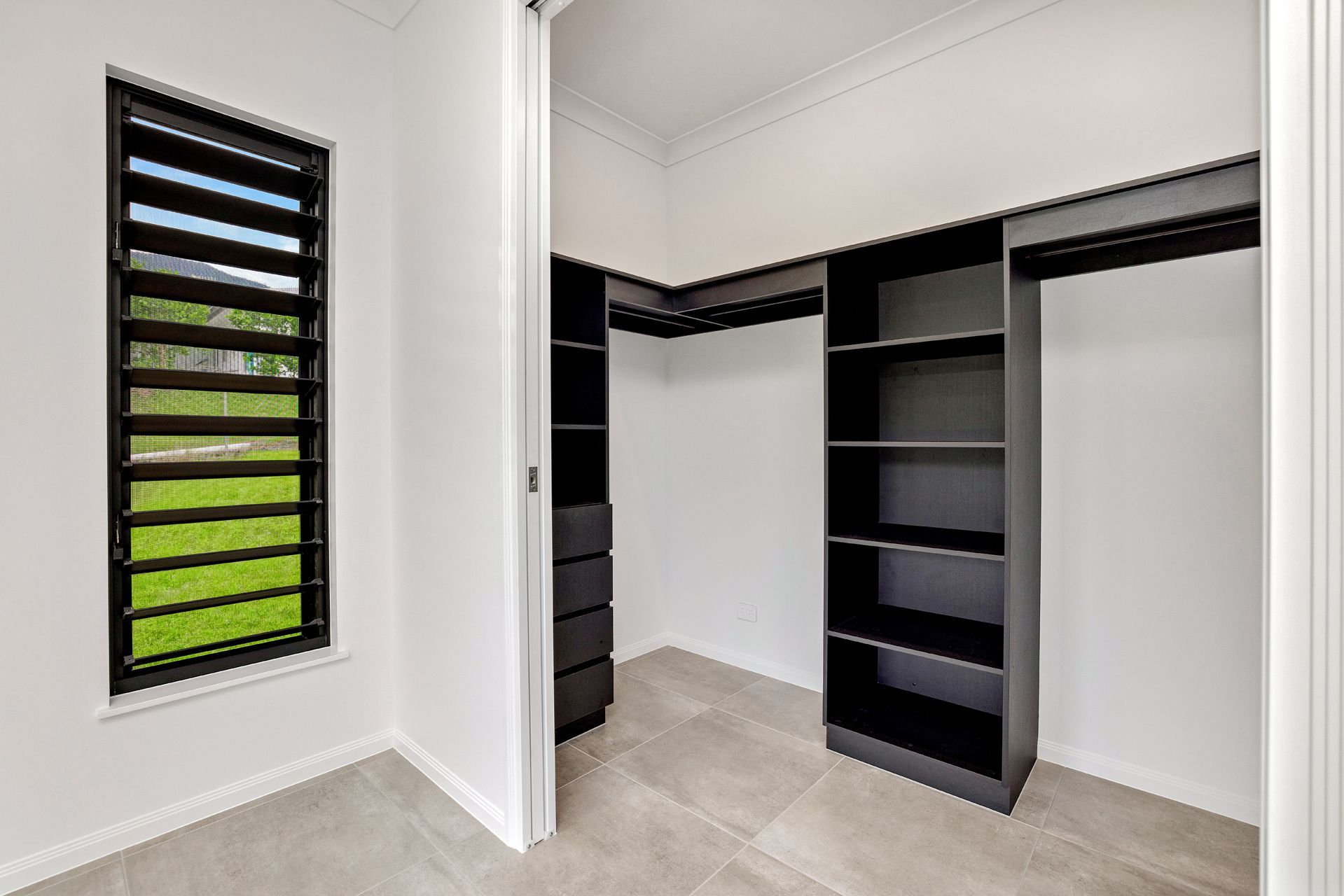 A Walk-in Closet With Black Shelving and Drawers — Ashlee Jones Homes in Gordonvale, QLD