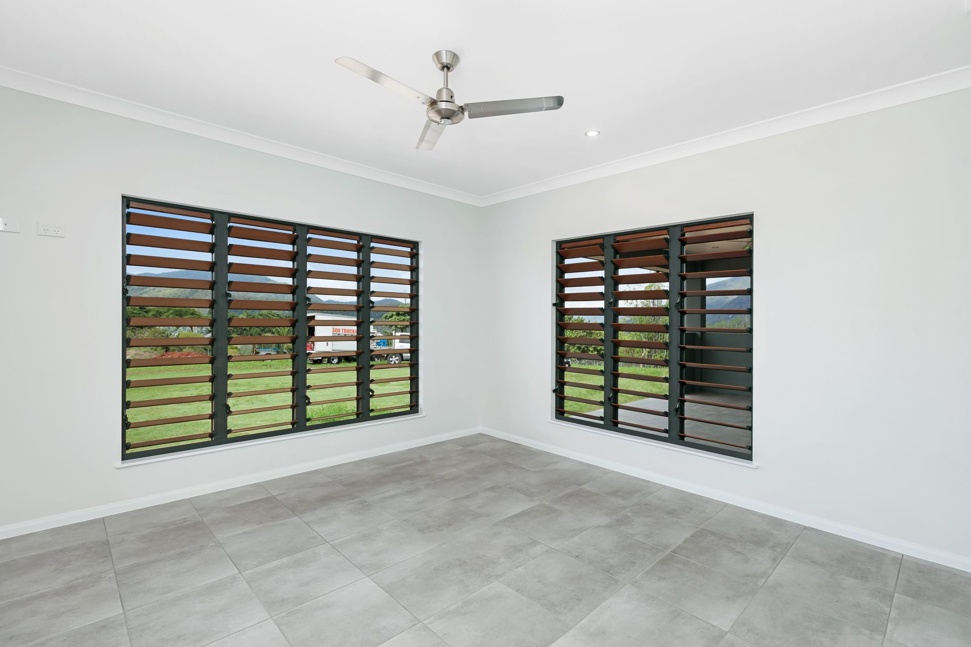 An Empty Room With Light Grey Walls, Grey Tiled Flooring — Ashlee Jones Homes in Gordonvale, QLD