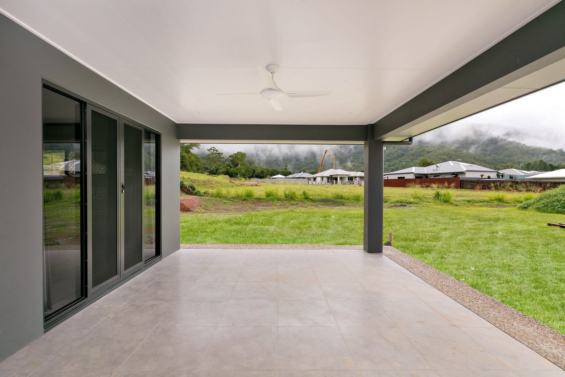 A Covered Outdoor Patio With Light Gray Tiled Flooring — Ashlee Jones Homes in Gordonvale, QLD