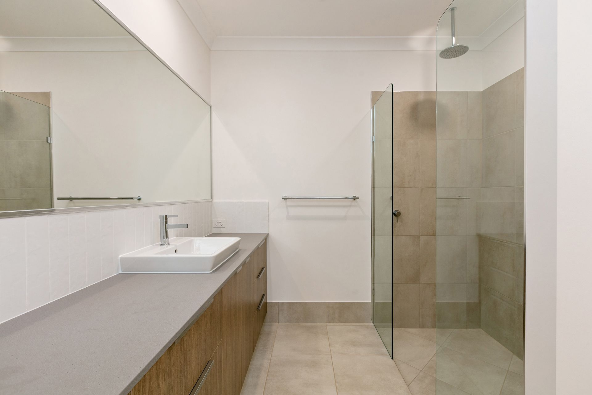 A Modern Bathroom With a Wood Vanity, Grey Countertop — Ashlee Jones Homes in Gordonvale, QLD