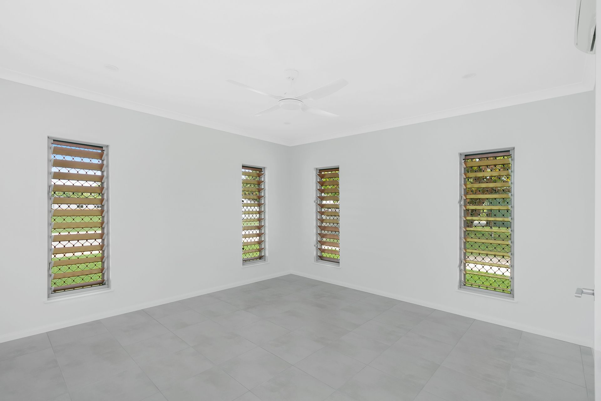 An Empty, Minimalist Room With Grey Tiled Flooring — Ashlee Jones Homes in Gordonvale, QLD