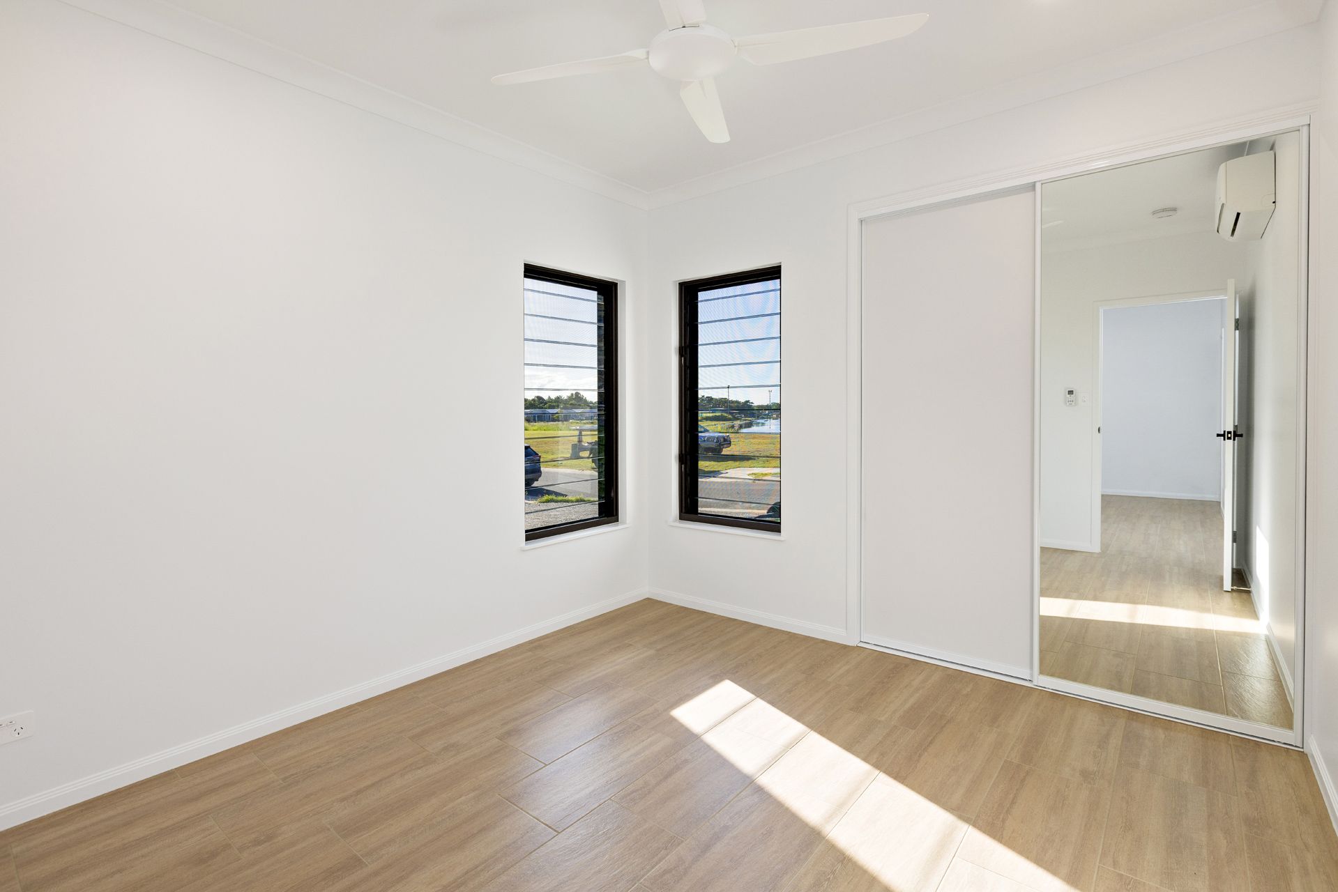 A Vacant, Minimalist Bedroom With Light Wood Flooring — Ashlee Jones Homes in Gordonvale, QLD
