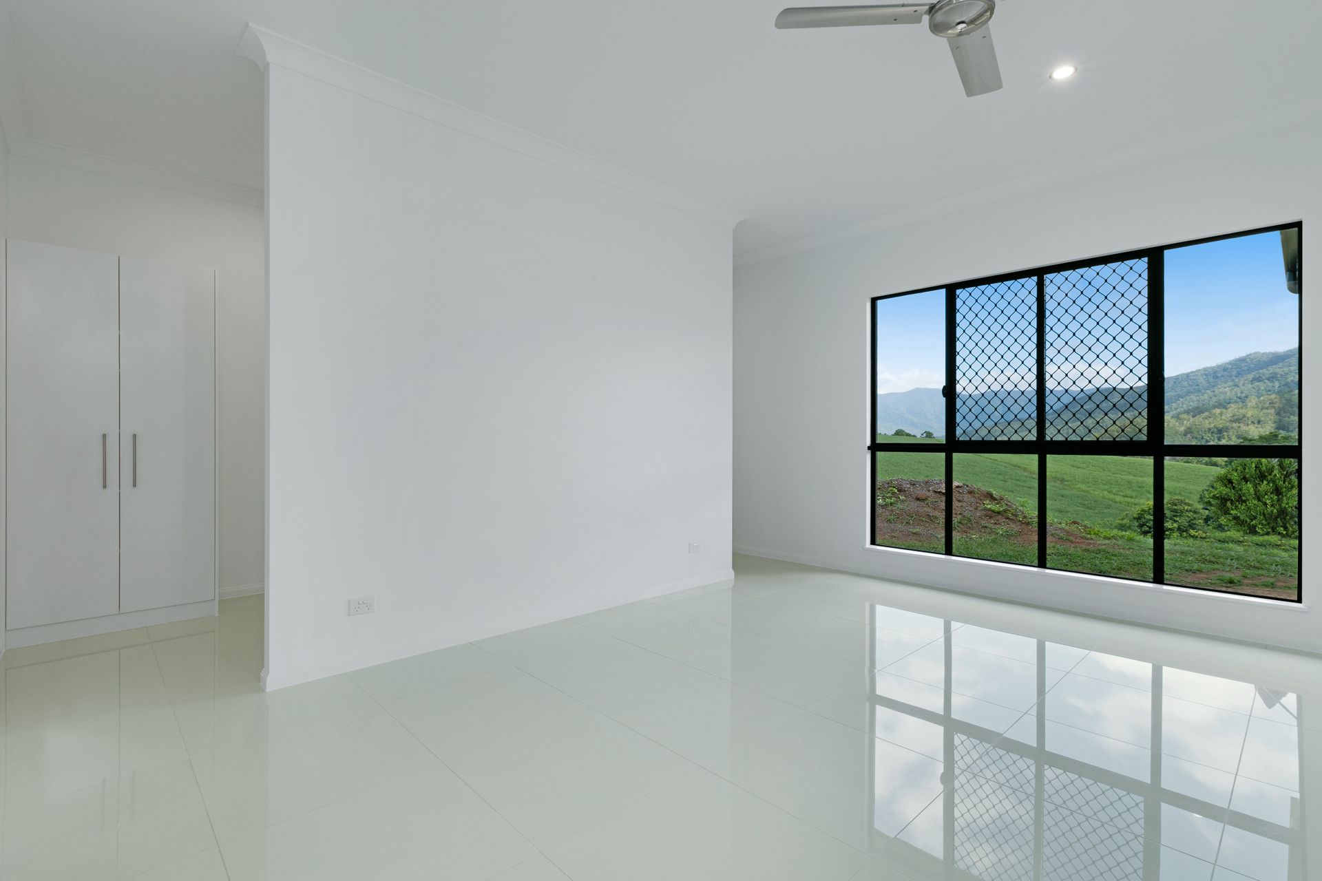 An Empty, Minimalist Bedroom With White Walls, Tiled Flooring — Ashlee Jones Homes in Gordonvale, QLD
