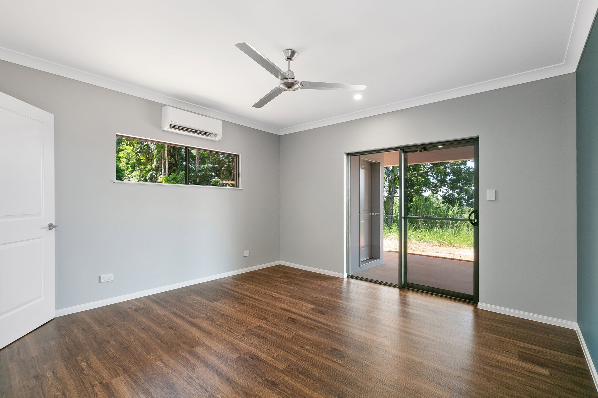 A Modern, Empty Room With Grey Walls, Dark Wood Floors, a Ceiling Fan — Ashlee Jones Homes in Gordonvale, QLD