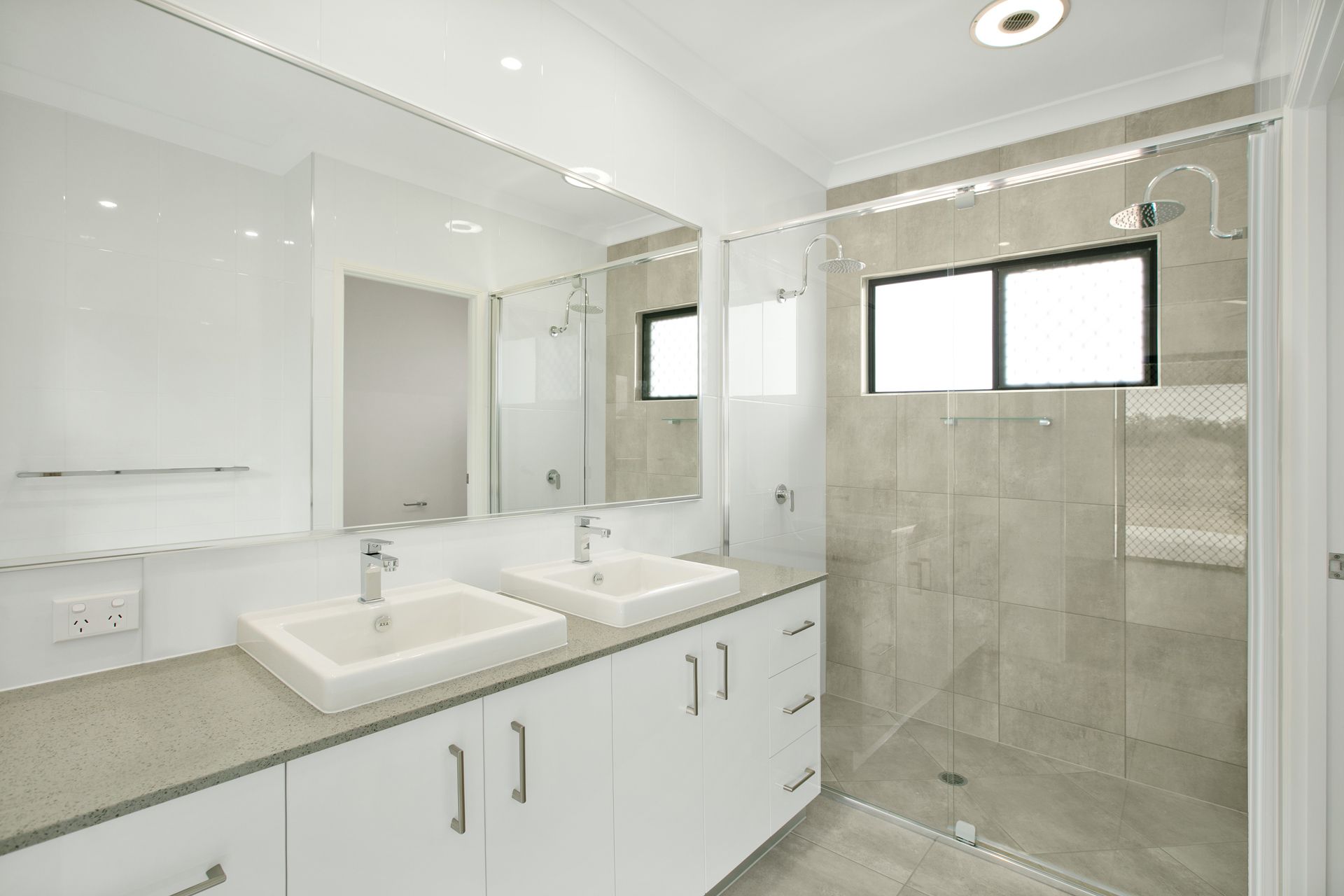 Modern Bathroom Featuring a Double Vanity With White Cabinets — Ashlee Jones Homes in Gordonvale, QLD