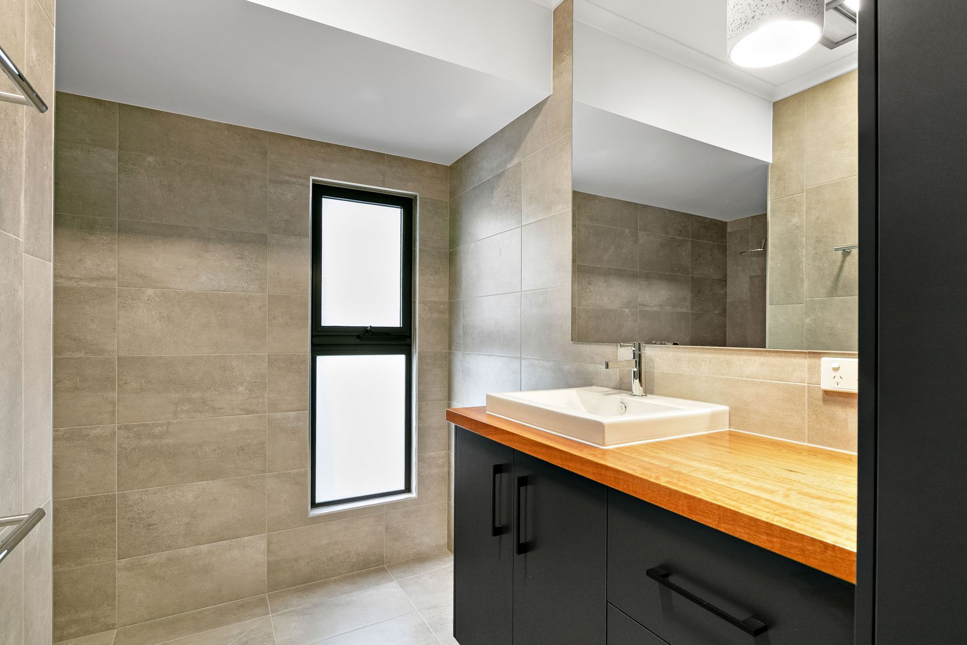 Modern Bathroom With a Wooden Vanity Countertop — Ashlee Jones Homes in Gordonvale, QLD