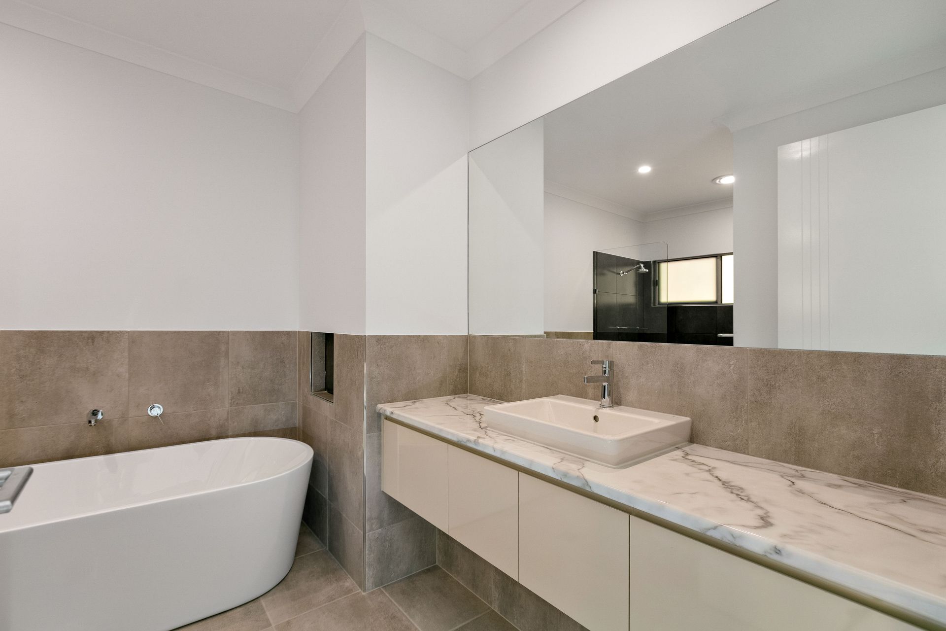A Modern Bathroom Featuring a White Soaking Tub — Ashlee Jones Homes in Gordonvale, QLD