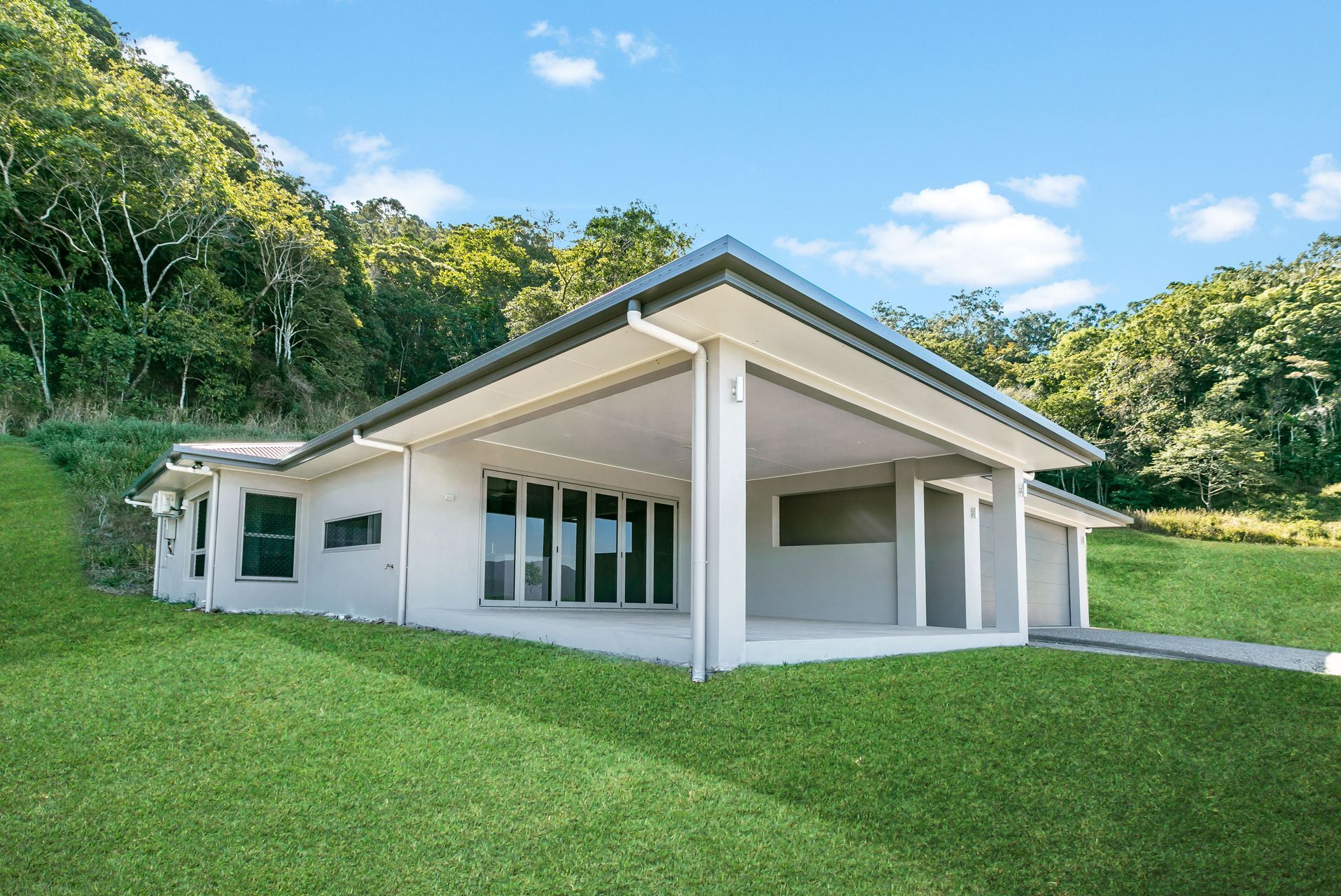 A White Single-story House With a Wide Covered Porch — Ashlee Jones Homes in Gordonvale, QLD