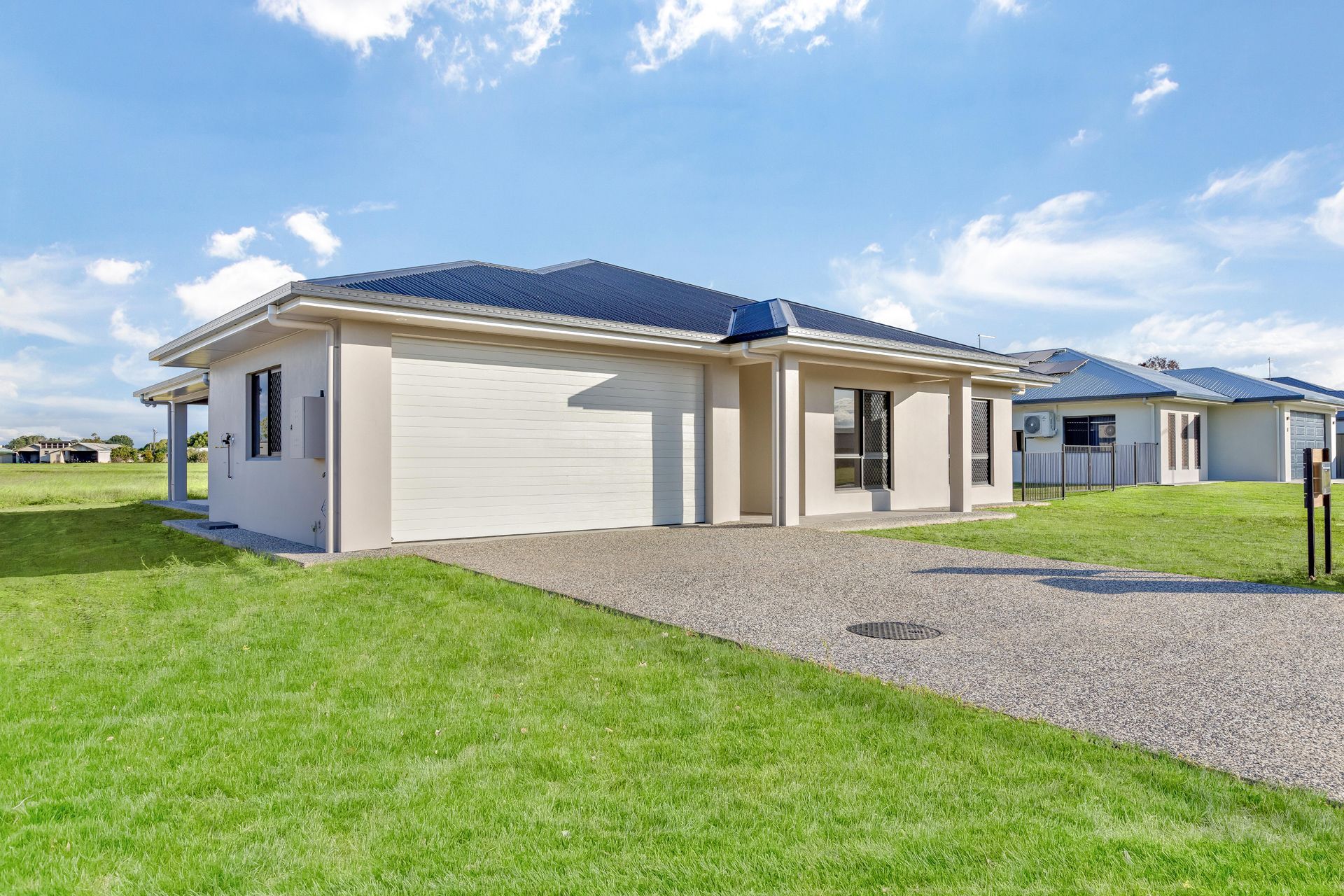 A Modern, Single-story Beige House With a Dark Roof and a Gravel Driveway Set — Ashlee Jones Homes in Gordonvale, QLD