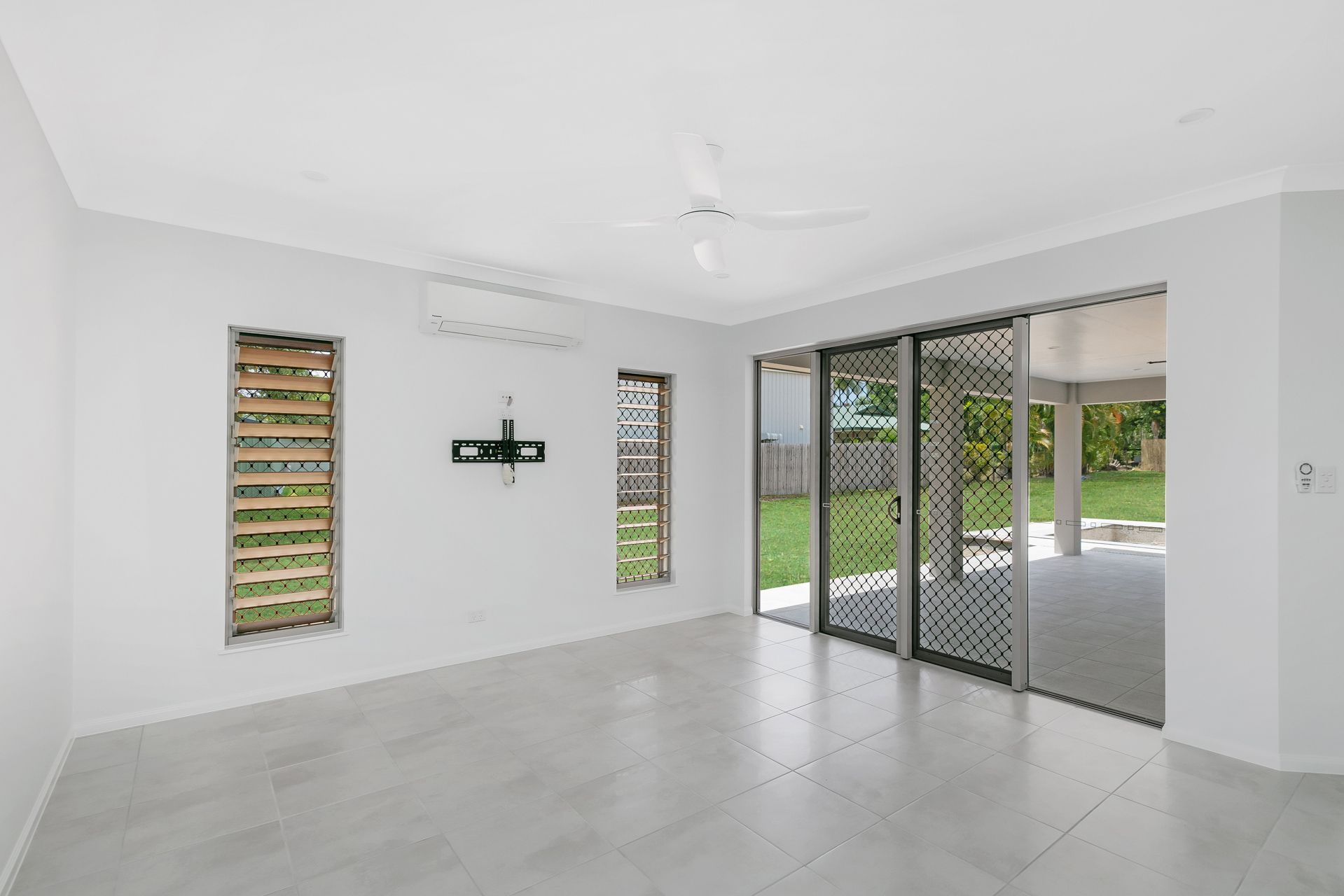 An Empty, Light-gray Room Featuring Four Vertical Louver Windows — Ashlee Jones Homes in Gordonvale, QLD