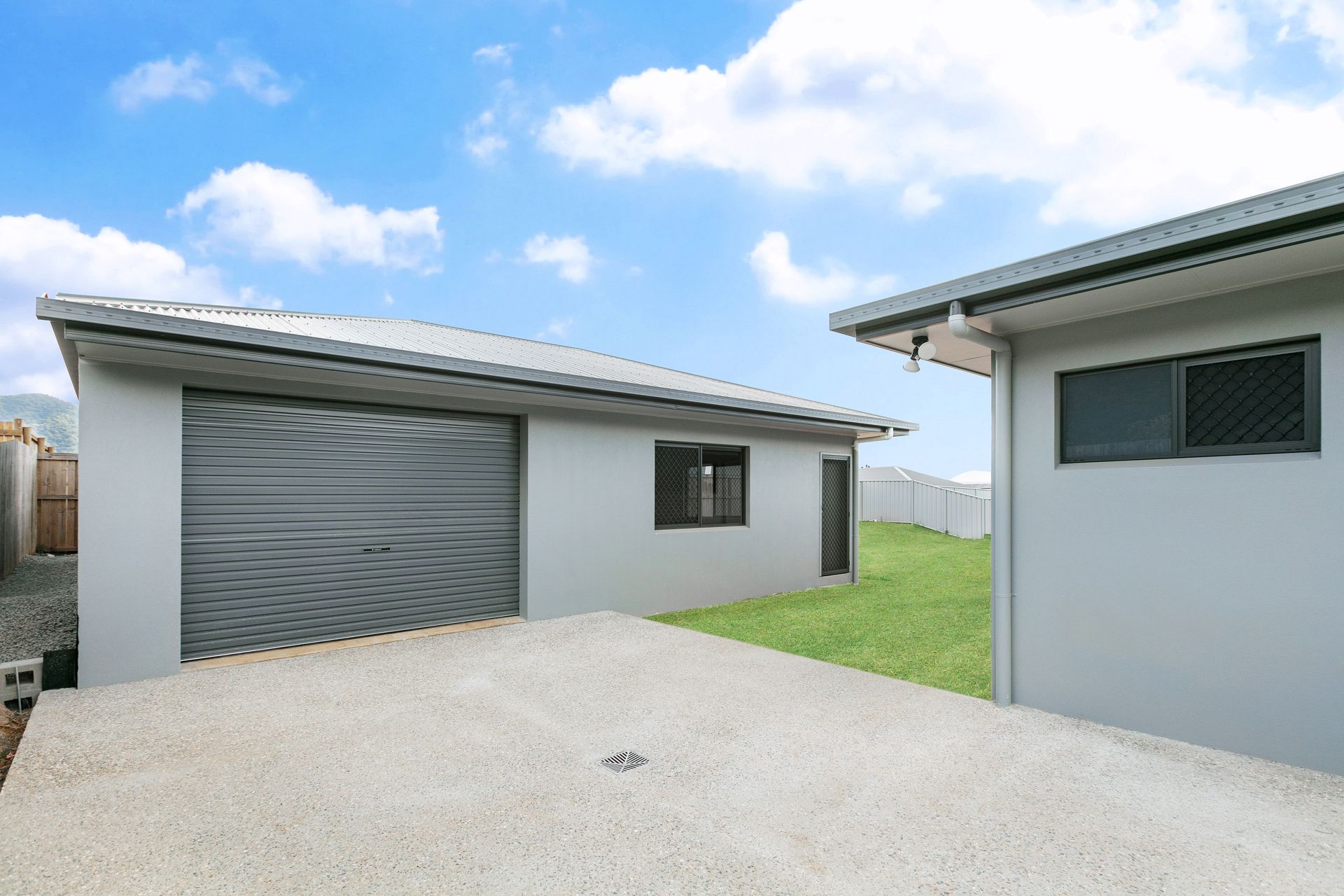 A Detached Gray Garage With a Closed Rolling Door — Ashlee Jones Homes in Gordonvale, QLD