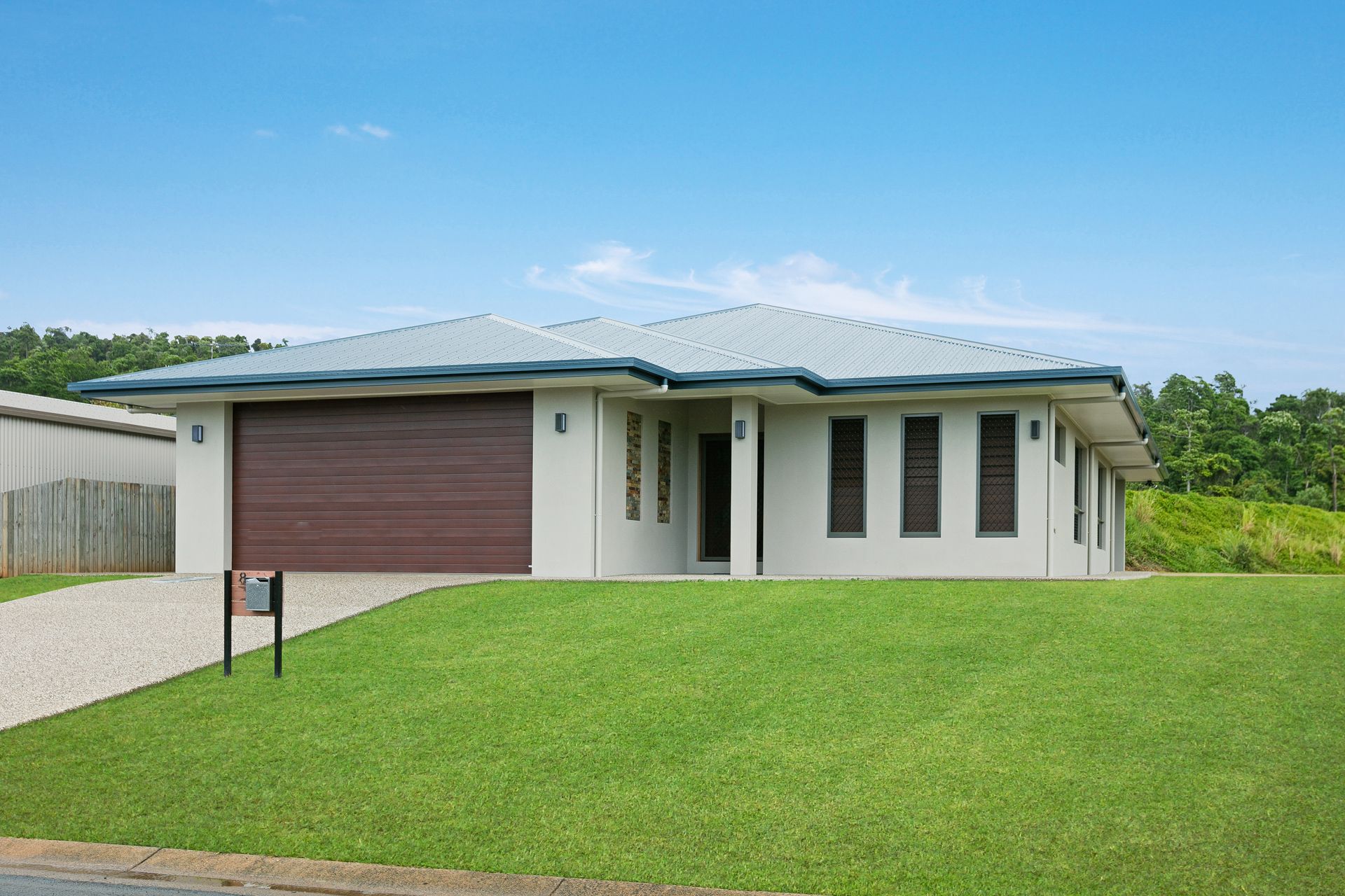 A Modern, Light-colored Single-story House With a Brown Garage Door — Ashlee Jones Homes in Gordonvale, QLD
