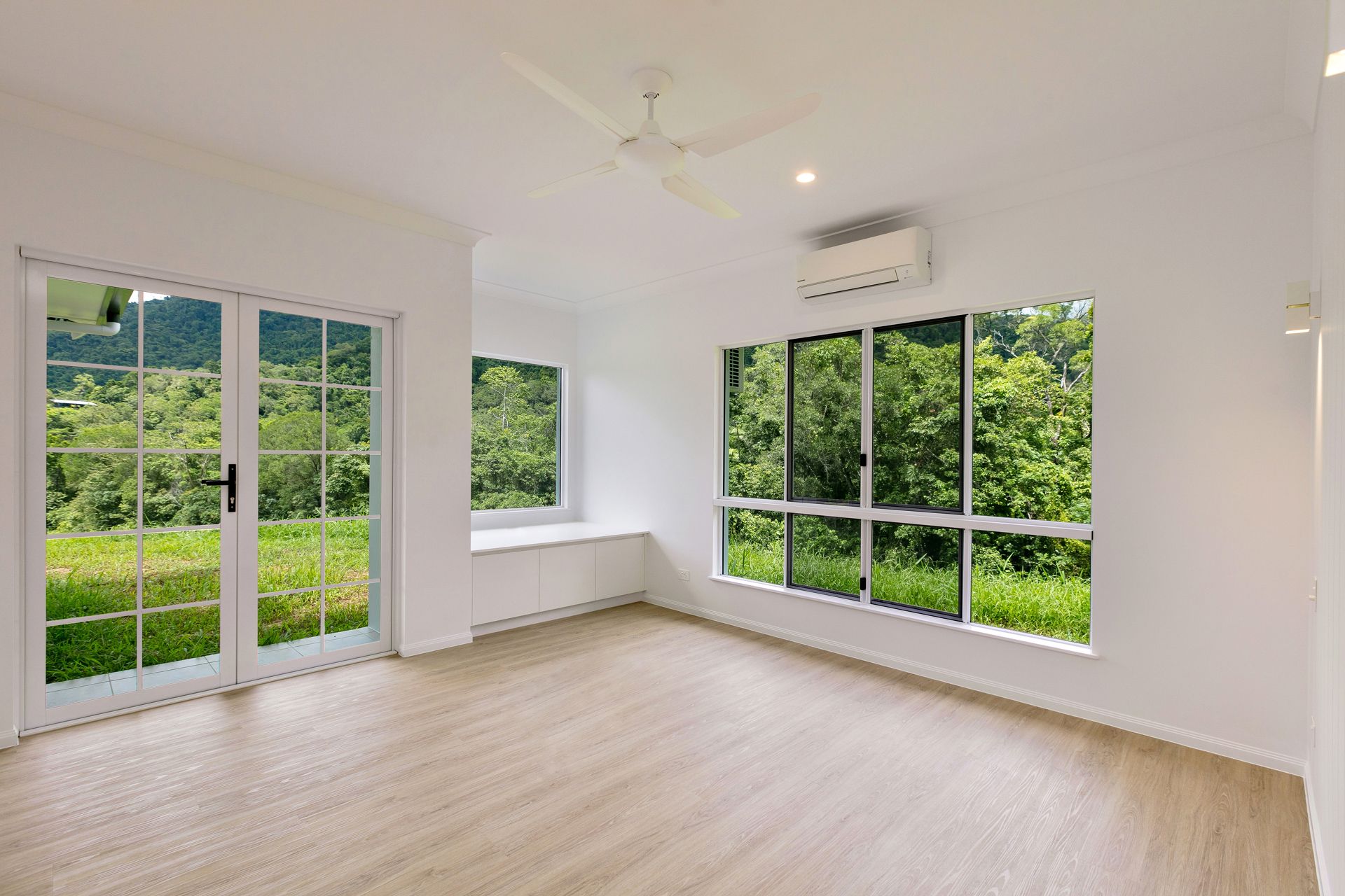 A Bright, Empty Room With White Walls, Light Wood Flooring — Ashlee Jones Homes in Gordonvale, QLD
