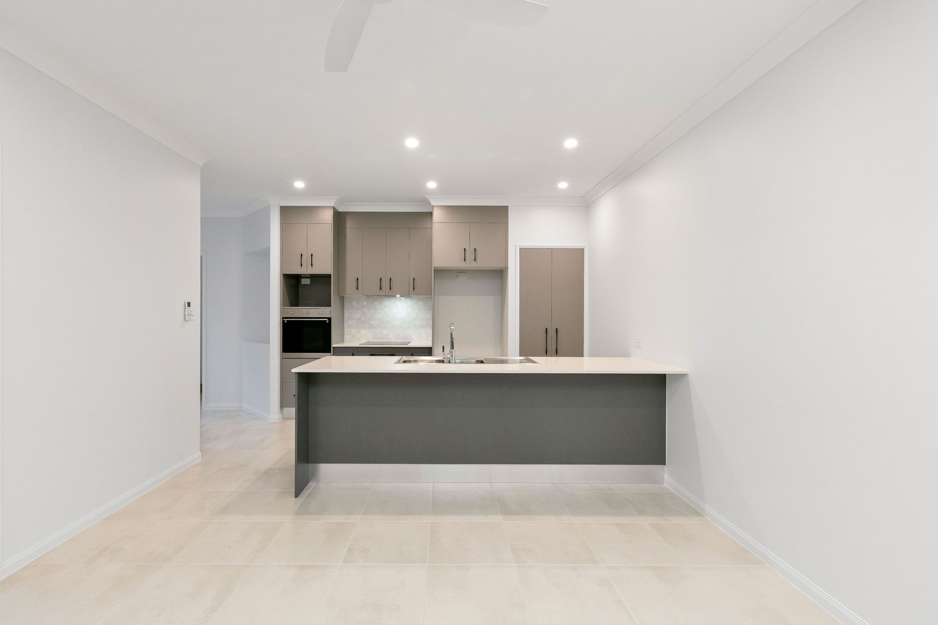 A Modern, Minimalist Kitchen Featuring Light-colored Flooring — Ashlee Jones Homes in Gordonvale, QLD