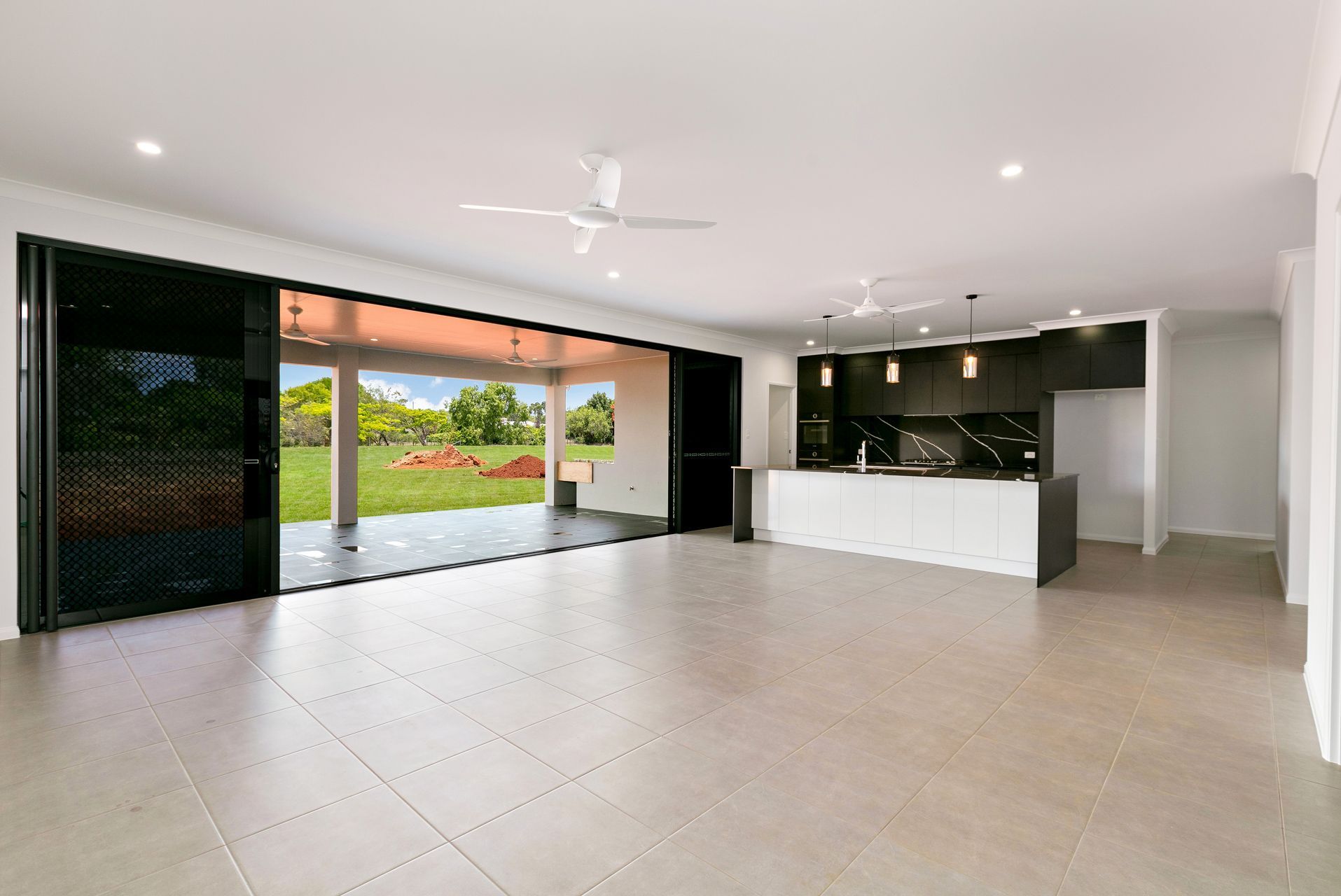 An Open-plan Living and Kitchen Area With Light Floor Tiles — Ashlee Jones Homes in Gordonvale, QLD
