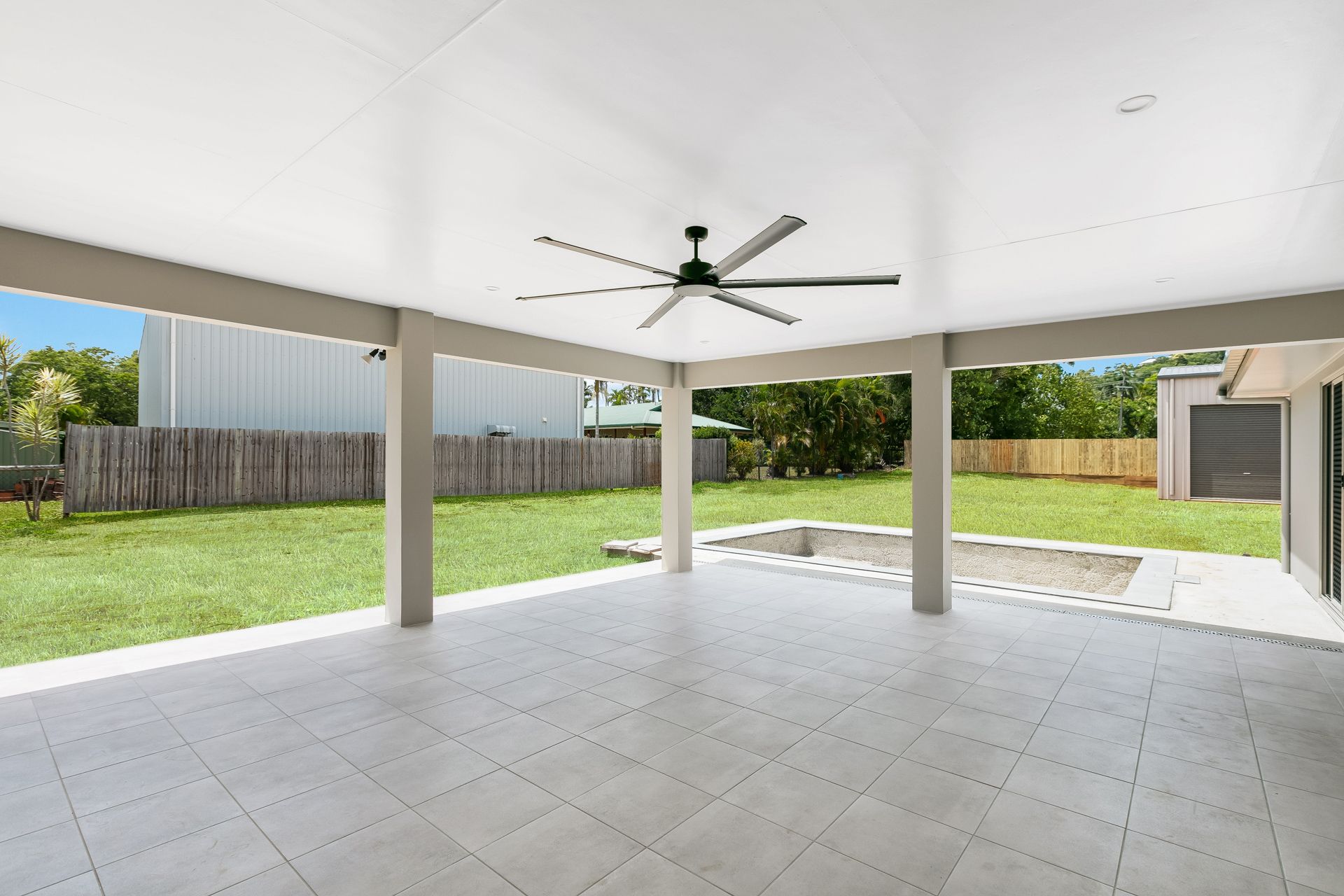 A Covered Patio With Light Grey Tiled Flooring — Ashlee Jones Homes in Gordonvale, QLD