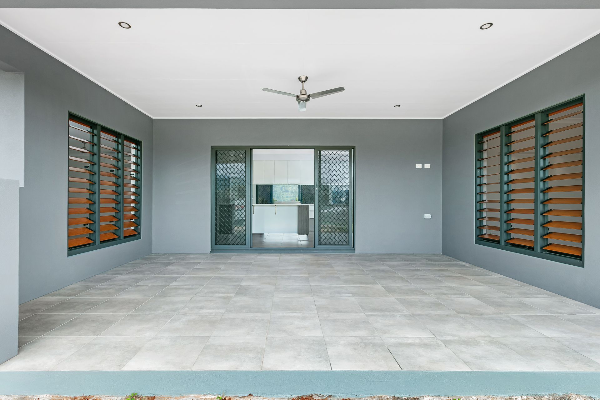 A Covered Outdoor Patio With Grey Walls, Light Tiled Flooring — Ashlee Jones Homes in Gordonvale, QLD