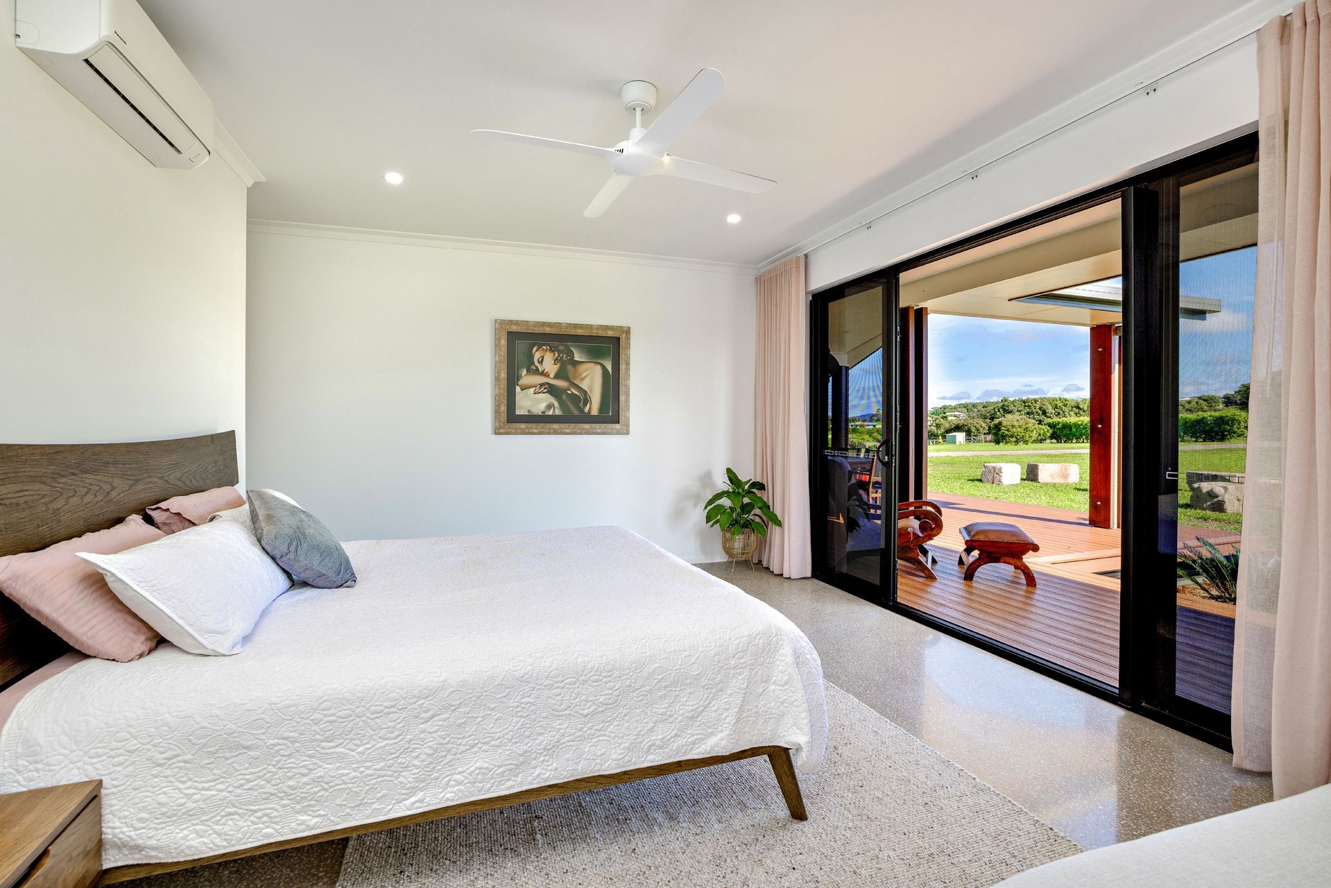 A Minimalist Bedroom With a Bed, Ceiling Fan — Ashlee Jones Homes in Gordonvale, QLD