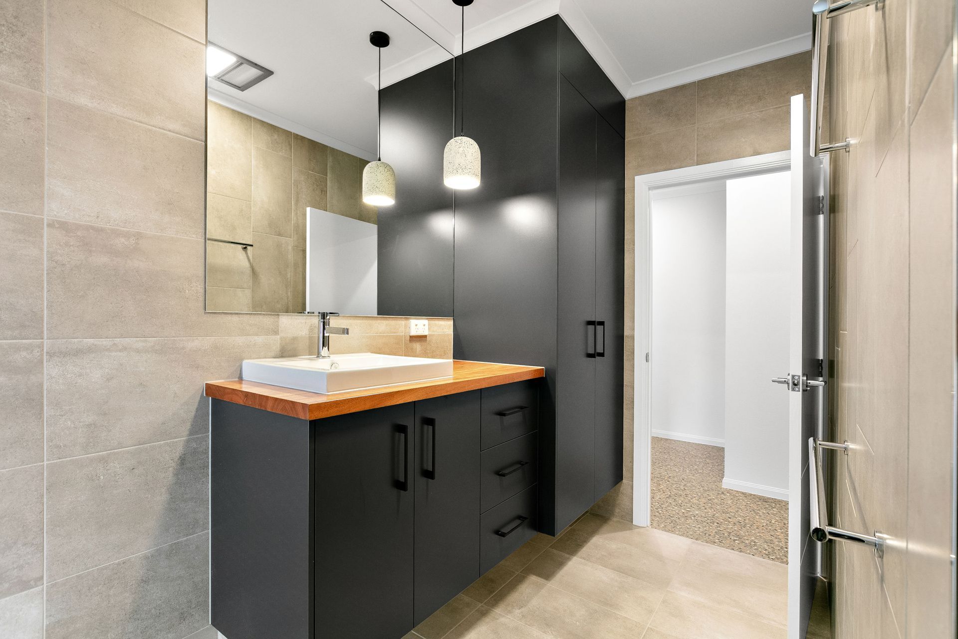 A Modern Bathroom With a Black Vanity, Wood Countertop — Ashlee Jones Homes in Gordonvale, QLD