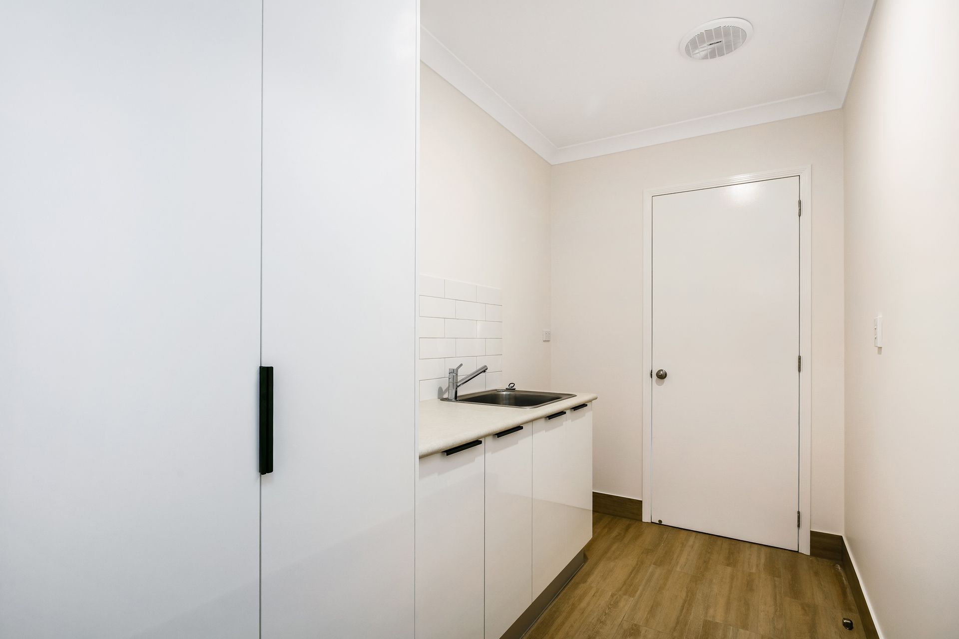 A Small, Minimalist Kitchen Area With White Cabinetry — Ashlee Jones Homes in Gordonvale, QLD