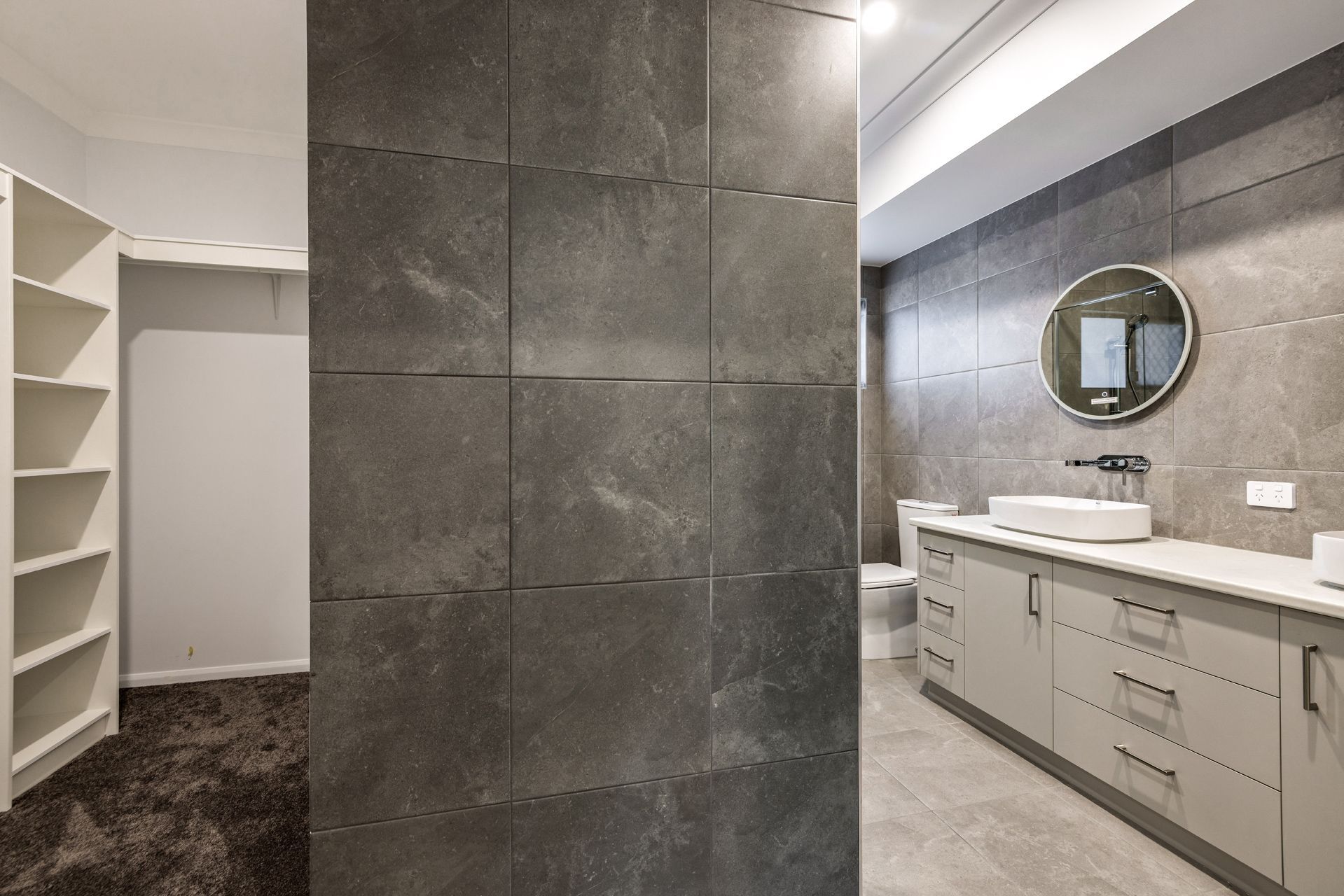 A Modern Bathroom Features a Dark Tiled Divider, Light Gray Vanity — Ashlee Jones Homes in Gordonvale, QLD