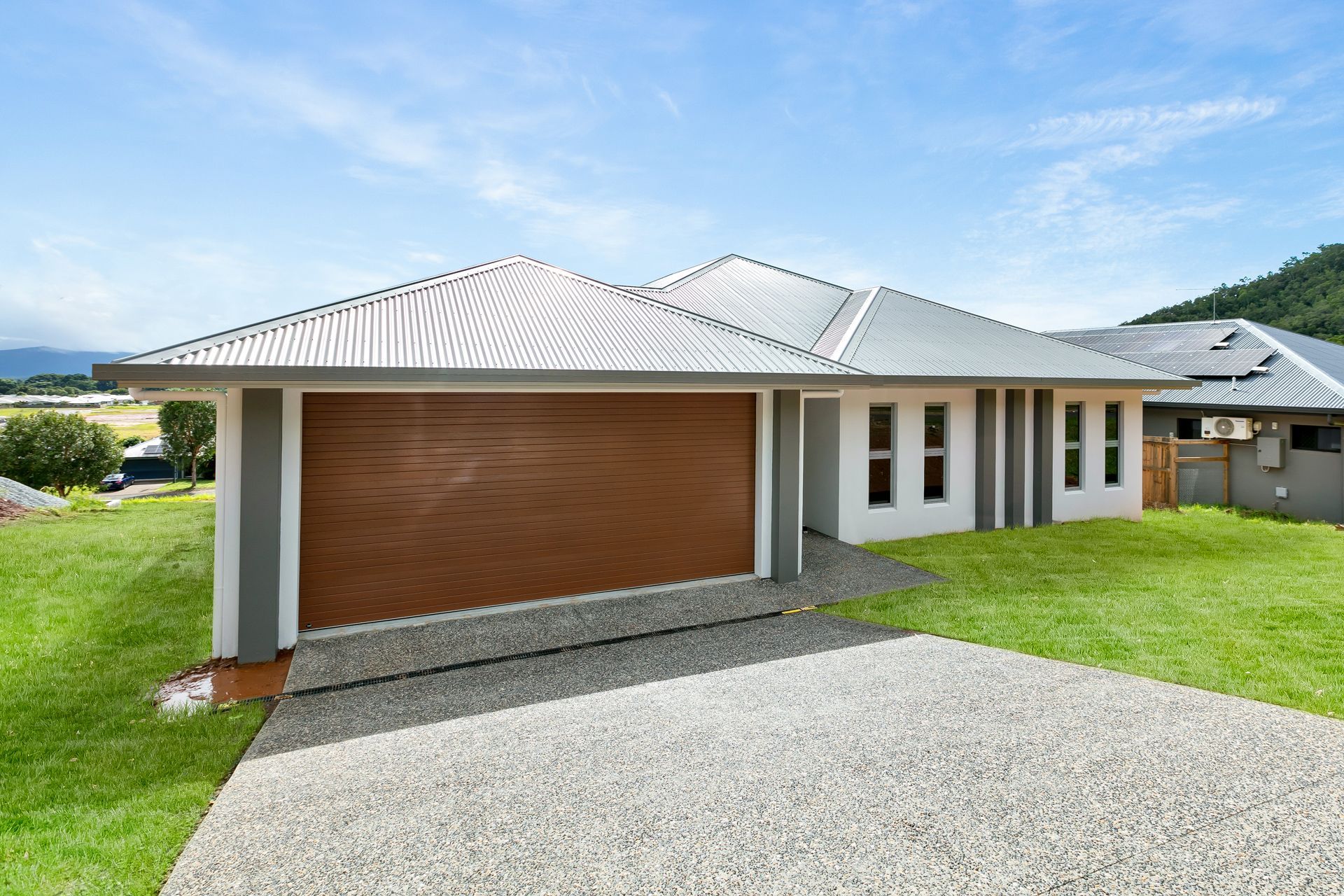 A Modern, Light-colored Single-story House With a Wooden Garage Door — Ashlee Jones Homes in Gordonvale, QLD