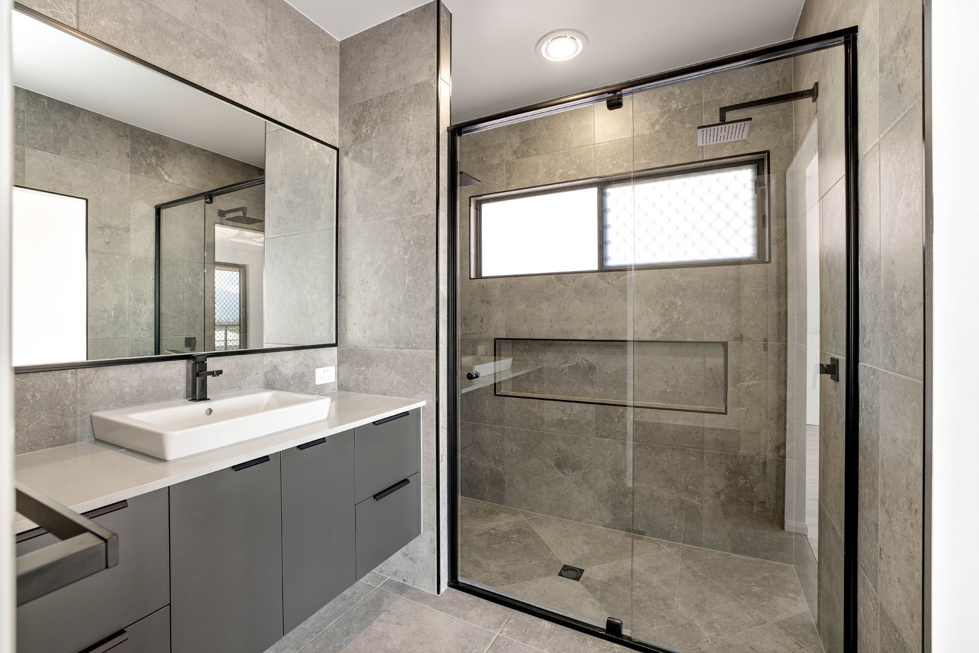 Modern Bathroom With Grey Stone Tiling, a White Vessel Sink on a Dark Vanity — Ashlee Jones Homes in Gordonvale, QLD