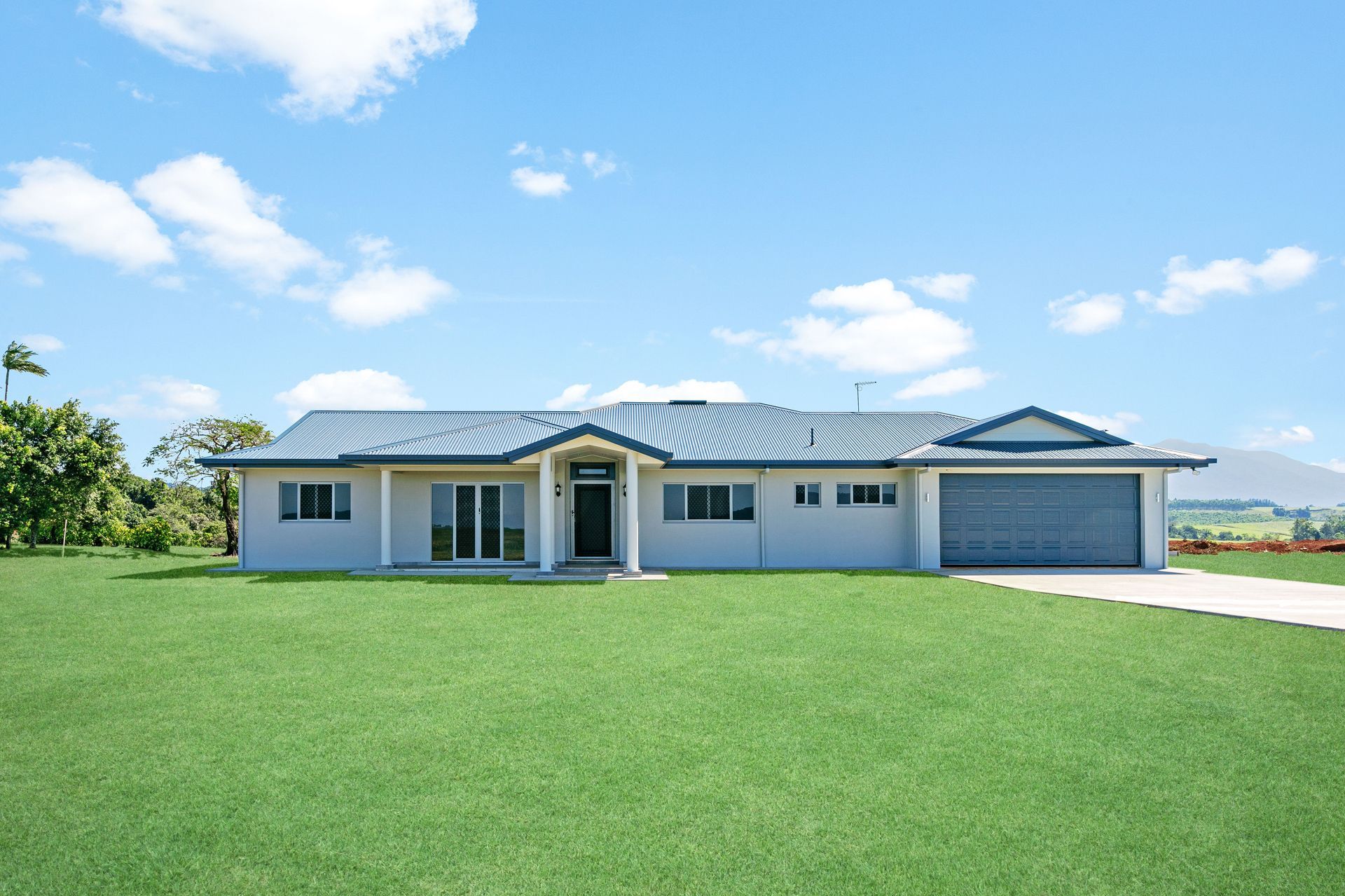A Light-colored Single-story House With a Blue Roof — Ashlee Jones Homes in Gordonvale, QLD