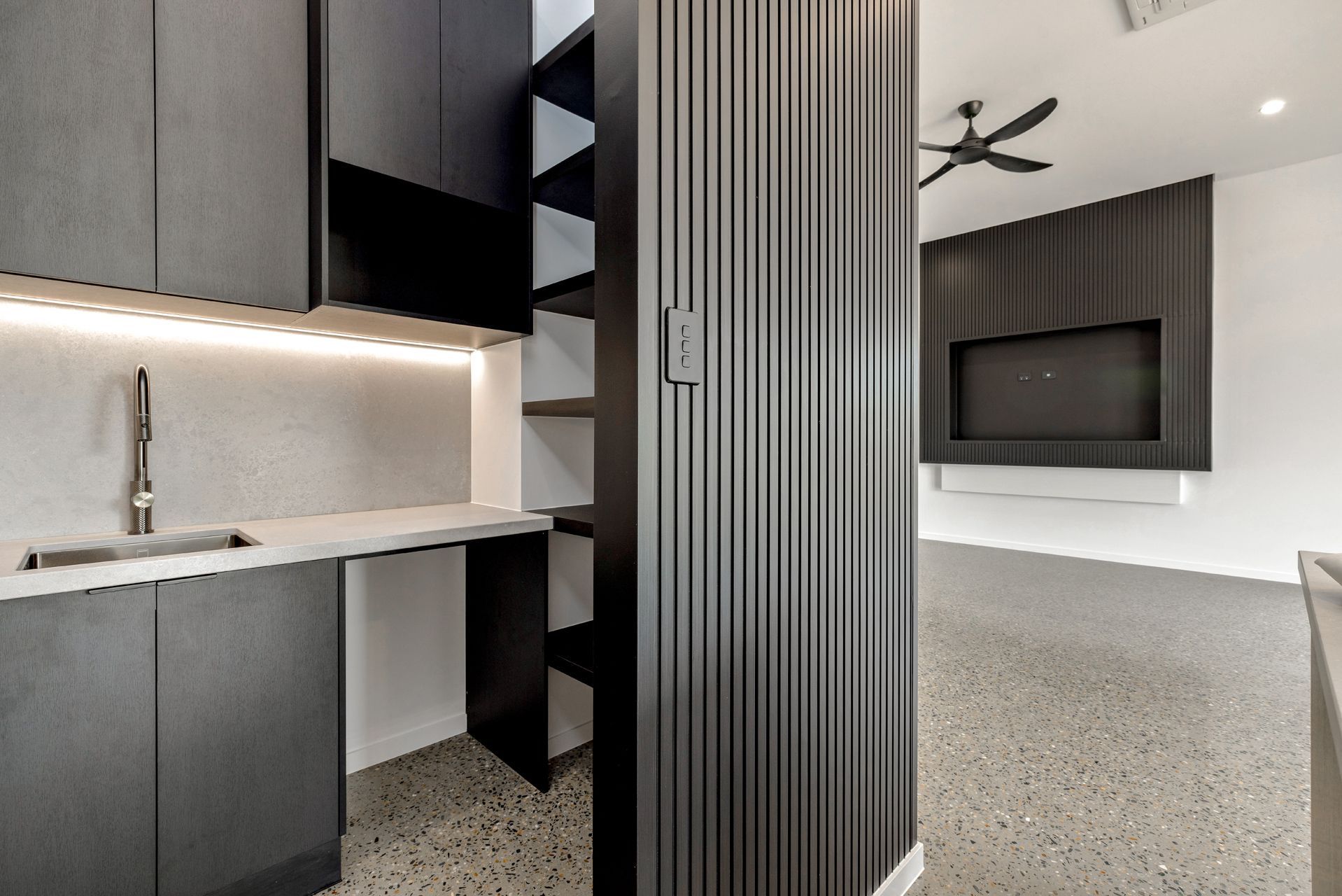 A Modern Kitchen Area With Dark Cabinets and a Fluted Accent Wall — Ashlee Jones Homes in Gordonvale, QLD