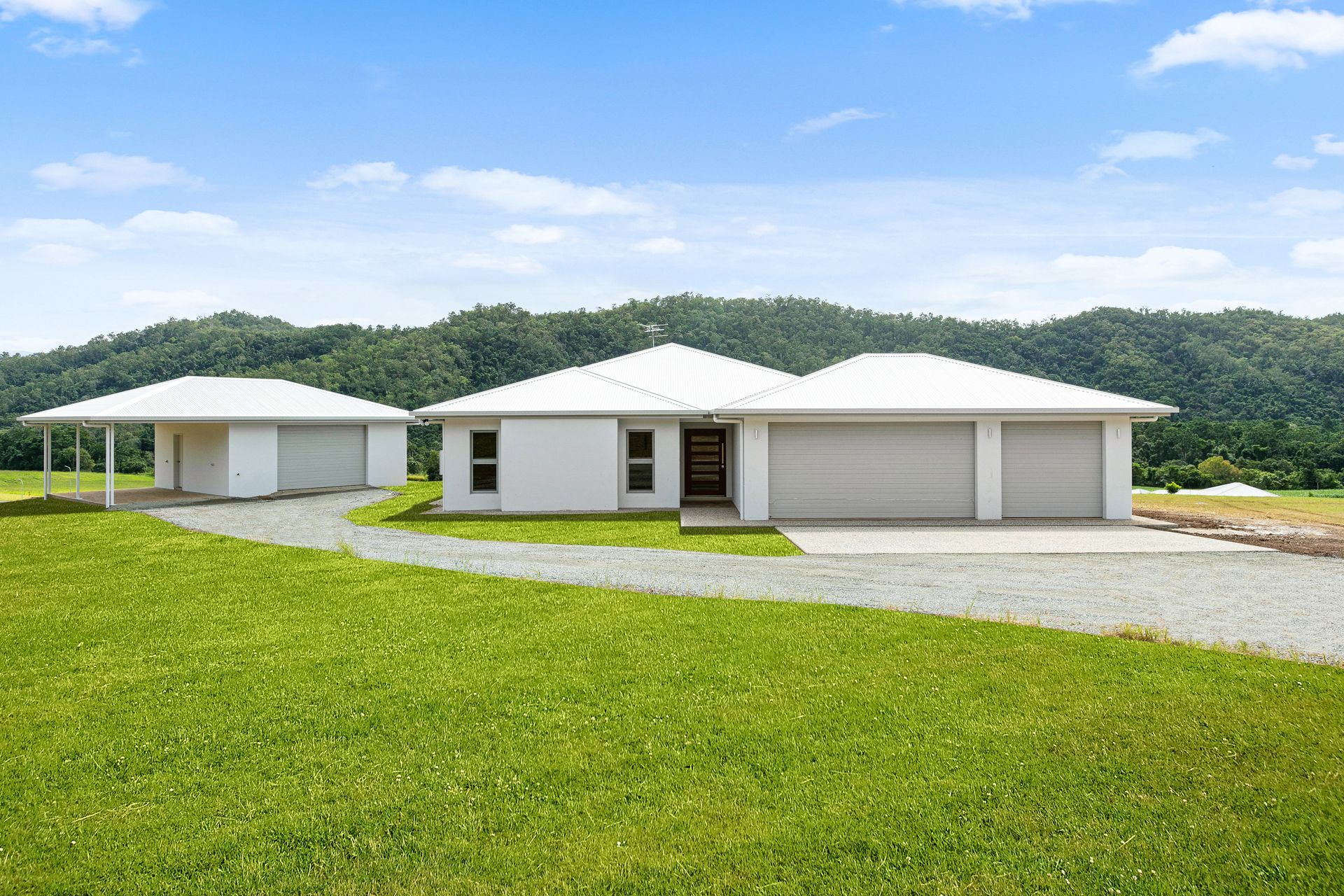 A Modern White House and Detached Carport Sit on a Green Lawn — Ashlee Jones Homes in Gordonvale, QLD