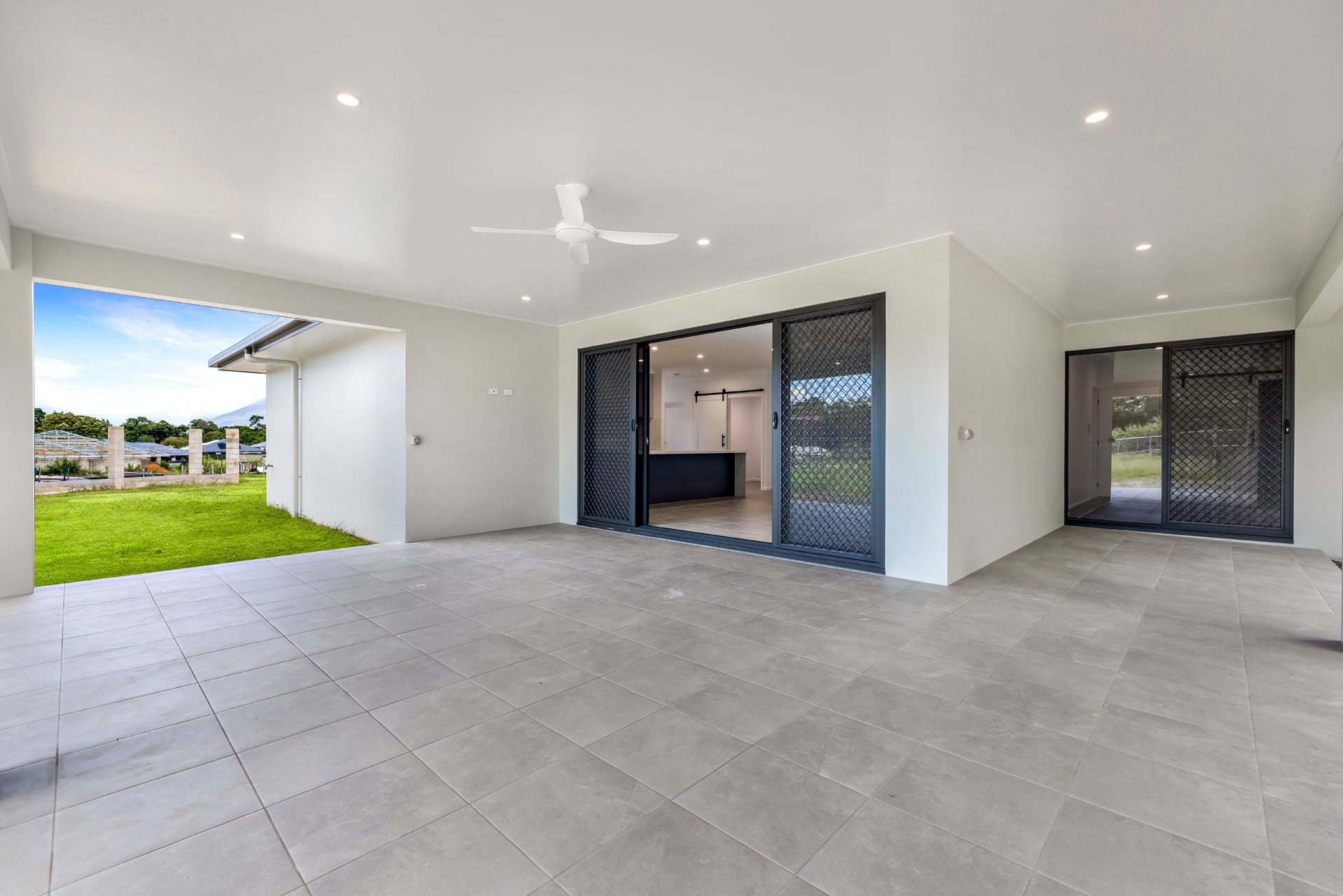 A Modern, Covered Outdoor Patio With Light Gray Floor Tiles — Ashlee Jones Homes in Gordonvale, QLD