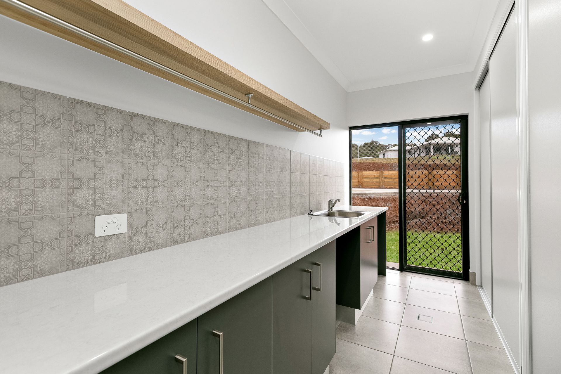 A Laundry Room With Dark Green Cabinets — Ashlee Jones Homes in Gordonvale, QLD