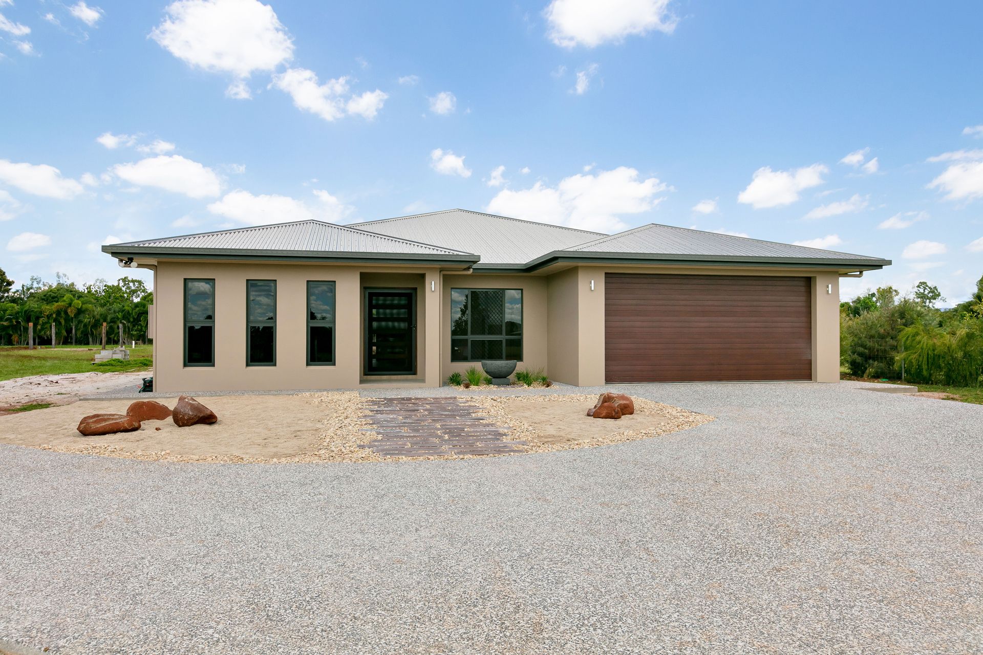 A Single-story, Beige Modern House With a Brown Garage Door — Ashlee Jones Homes in Gordonvale, QLD