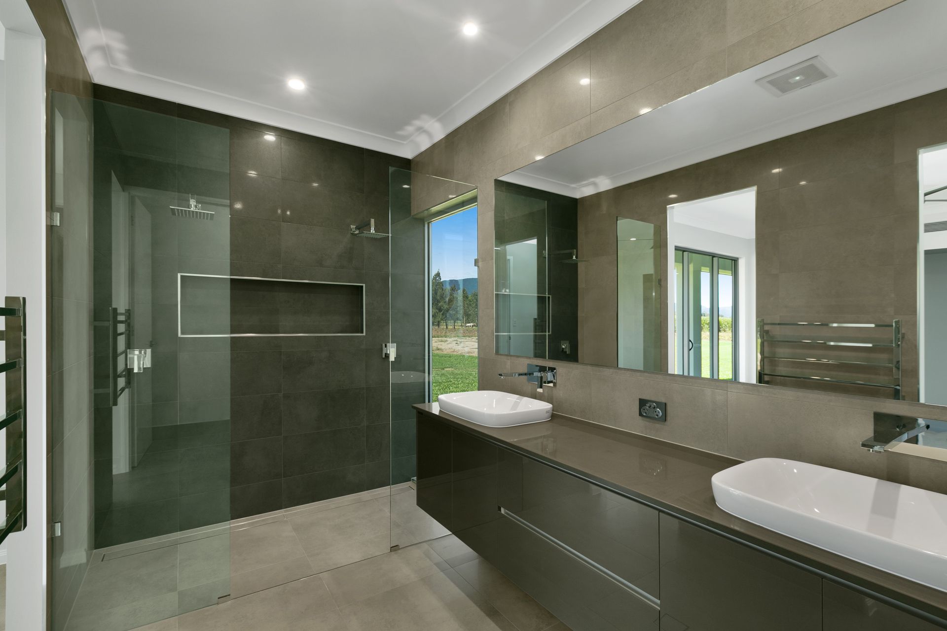 A Modern Bathroom With Dark Grey Tiled Walls, a Glass Shower — Ashlee Jones Homes in Gordonvale, QLD