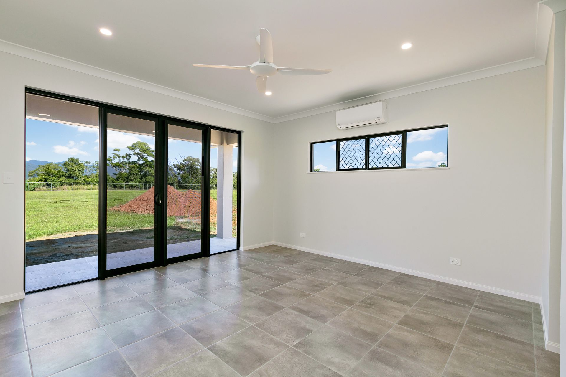 An Unfurnished Room With Gray Tile Flooring, White Walls — Ashlee Jones Homes in Gordonvale, QLD