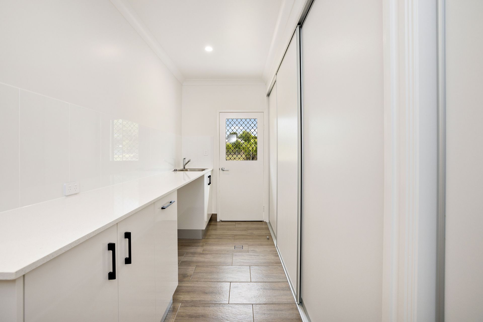 A Laundry Room With White Cabinets, a Light Wood-look Floor — Ashlee Jones Homes in Gordonvale, QLD